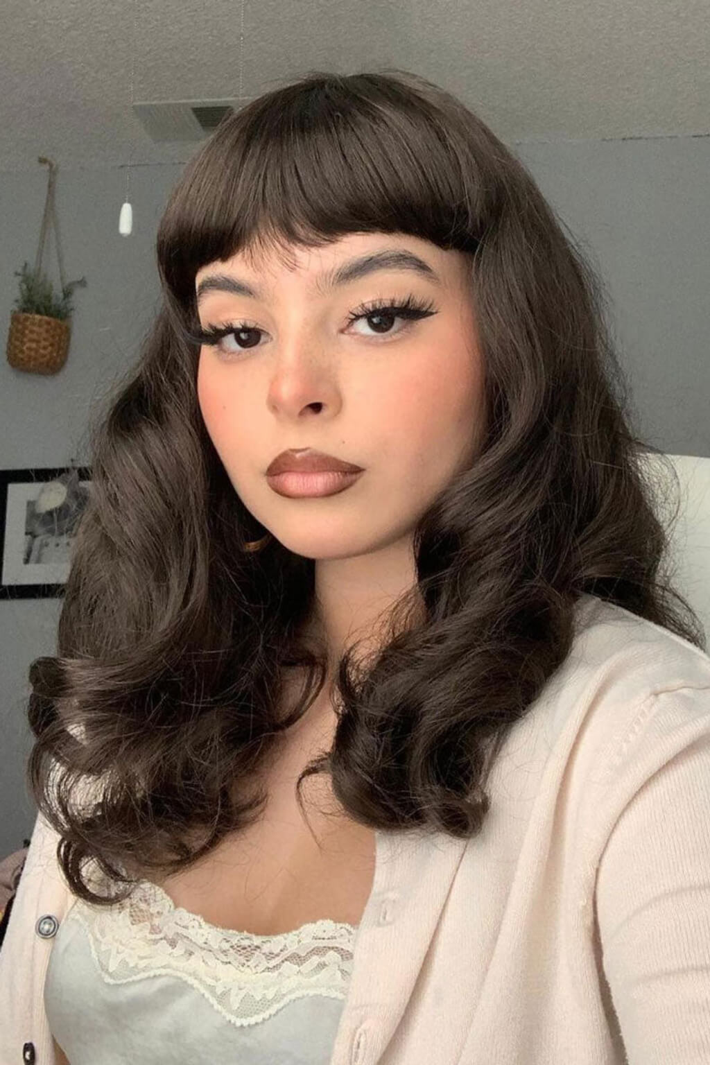 Woman with long, wavy hair and bangs. Dark brown pinup style wig, finger waved with short fringe, 1950s style: Becca