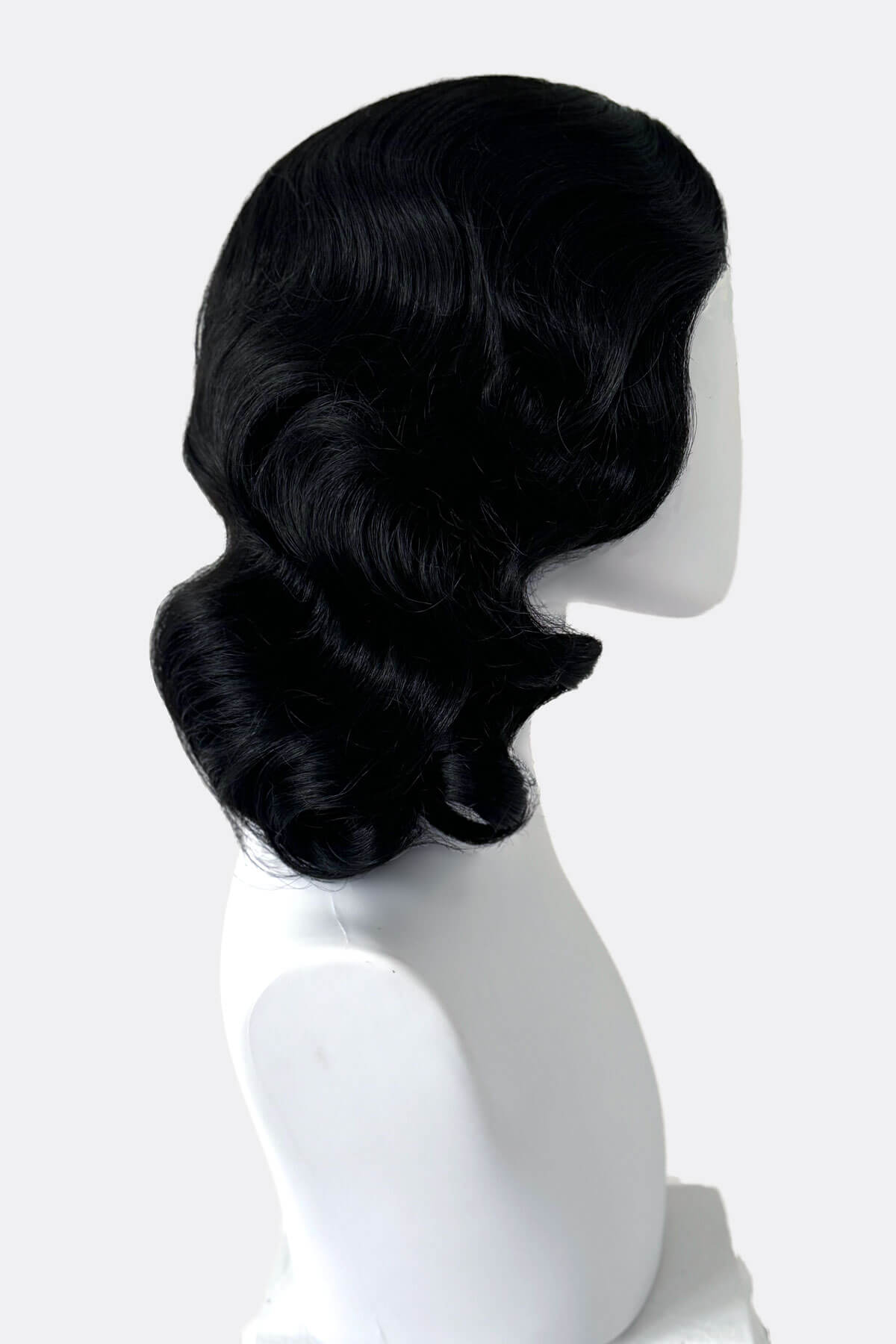 Black wig on a mannequin head against a white background. Black 40s style wig with beautiful marcel waves: Dita