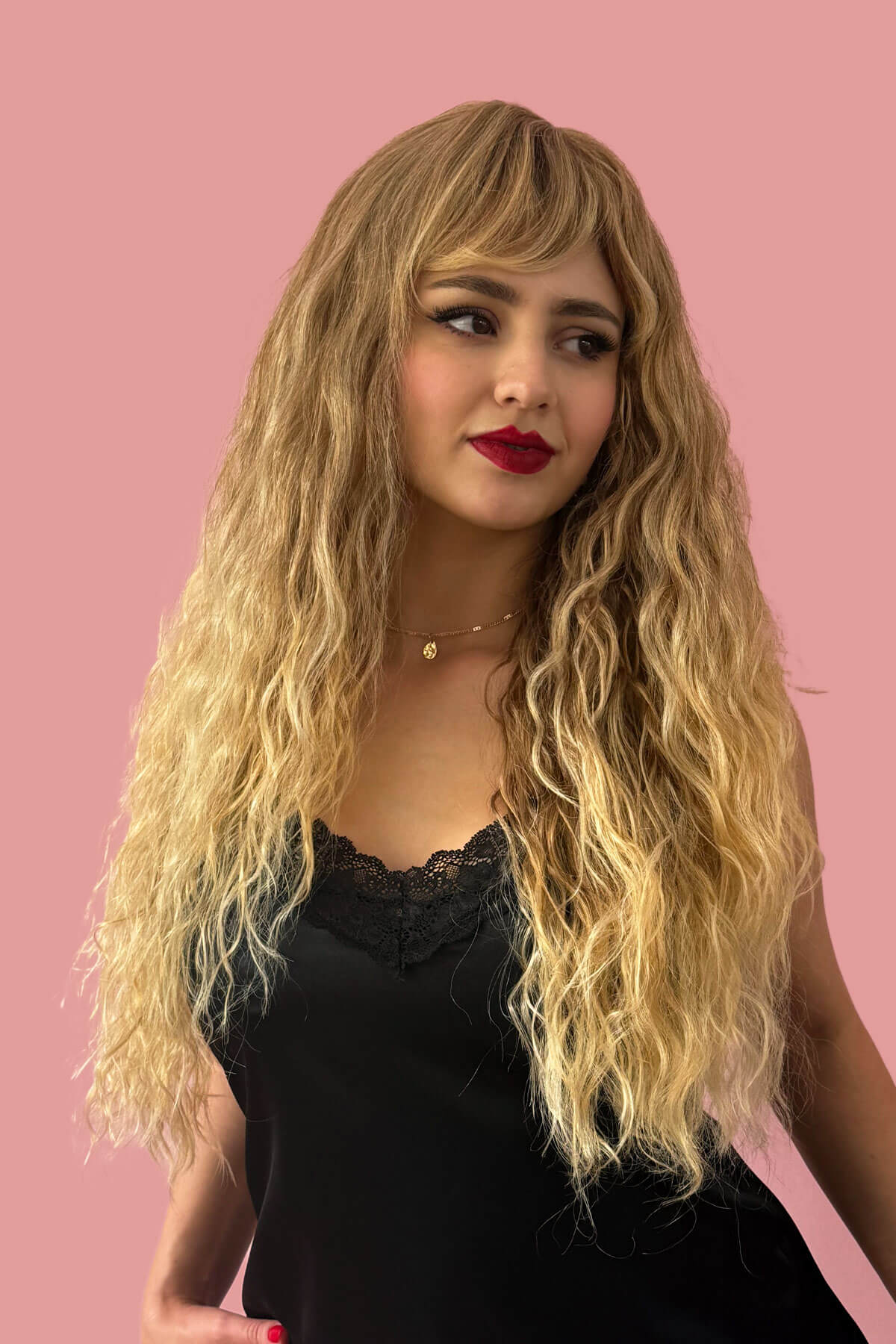 Woman with long blonde wig and red lipstick against a pink background. Long brown crimped wig, brown and blonde dip dye (ombre): Tiggy