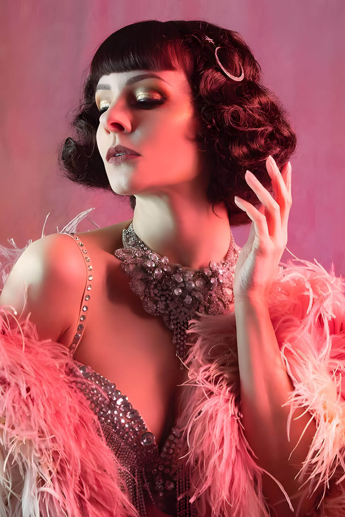 Woman in a glamorous outfit with a feather boa against a pink background. A short brown vintage style wig with waves: Rita chestnut brown 8