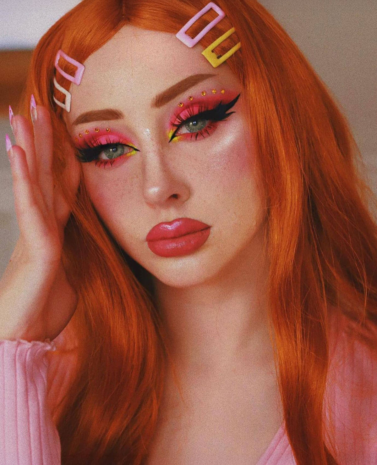 Person with red hair and colourful makeup, wearing a pink shirt. Long ginger wig with loose waves and curls: Ginger