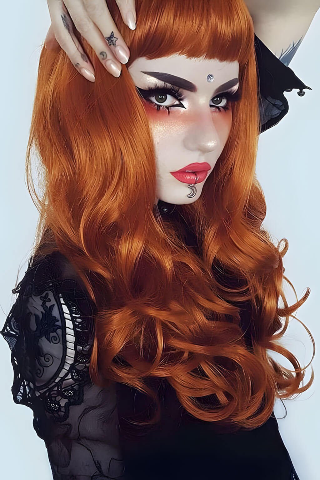 Person with red hair and black lace garment on a light gray background. Long ginger wig with loose waves and curls: Ginger