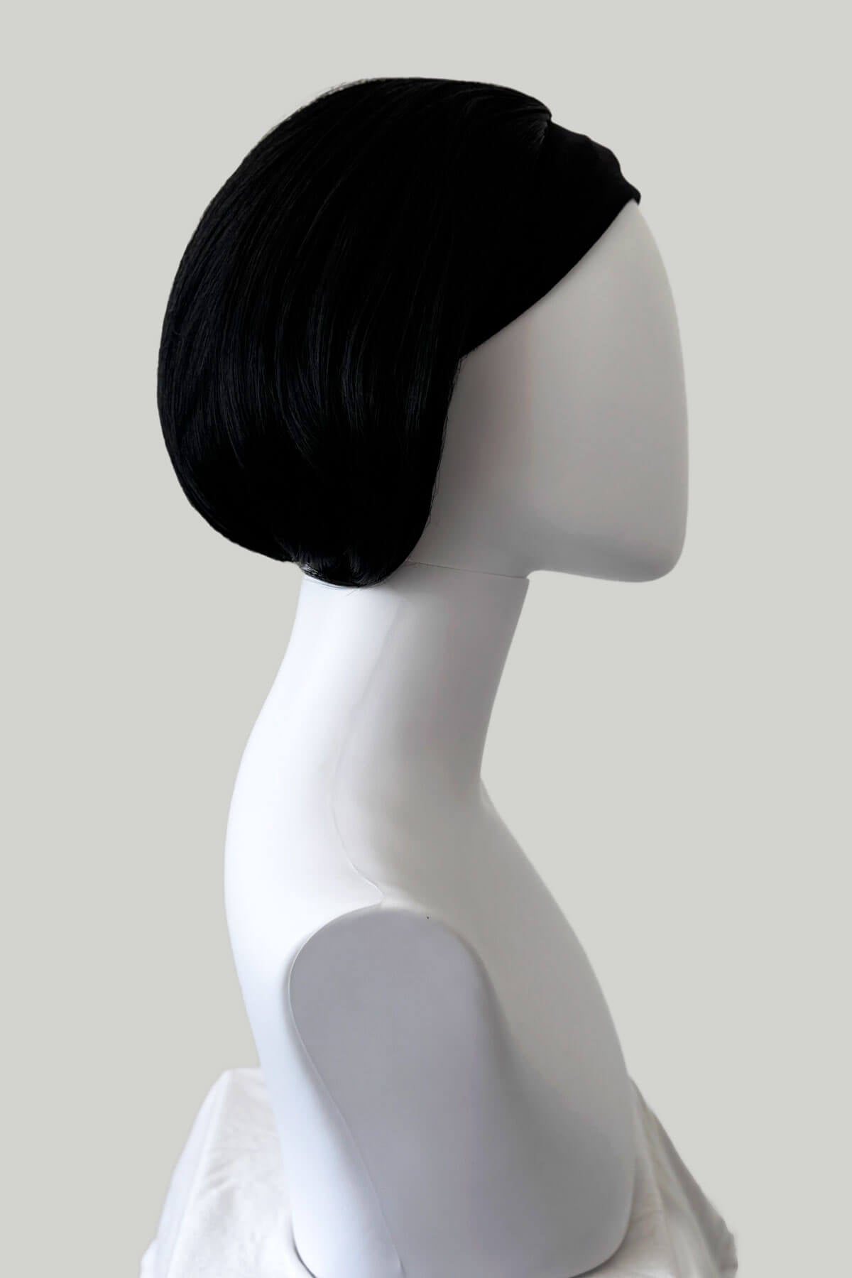 Black wig on a mannequin head from the side against a white background. Bob half wig hairpiece, Flexihair: Amelie black 1b