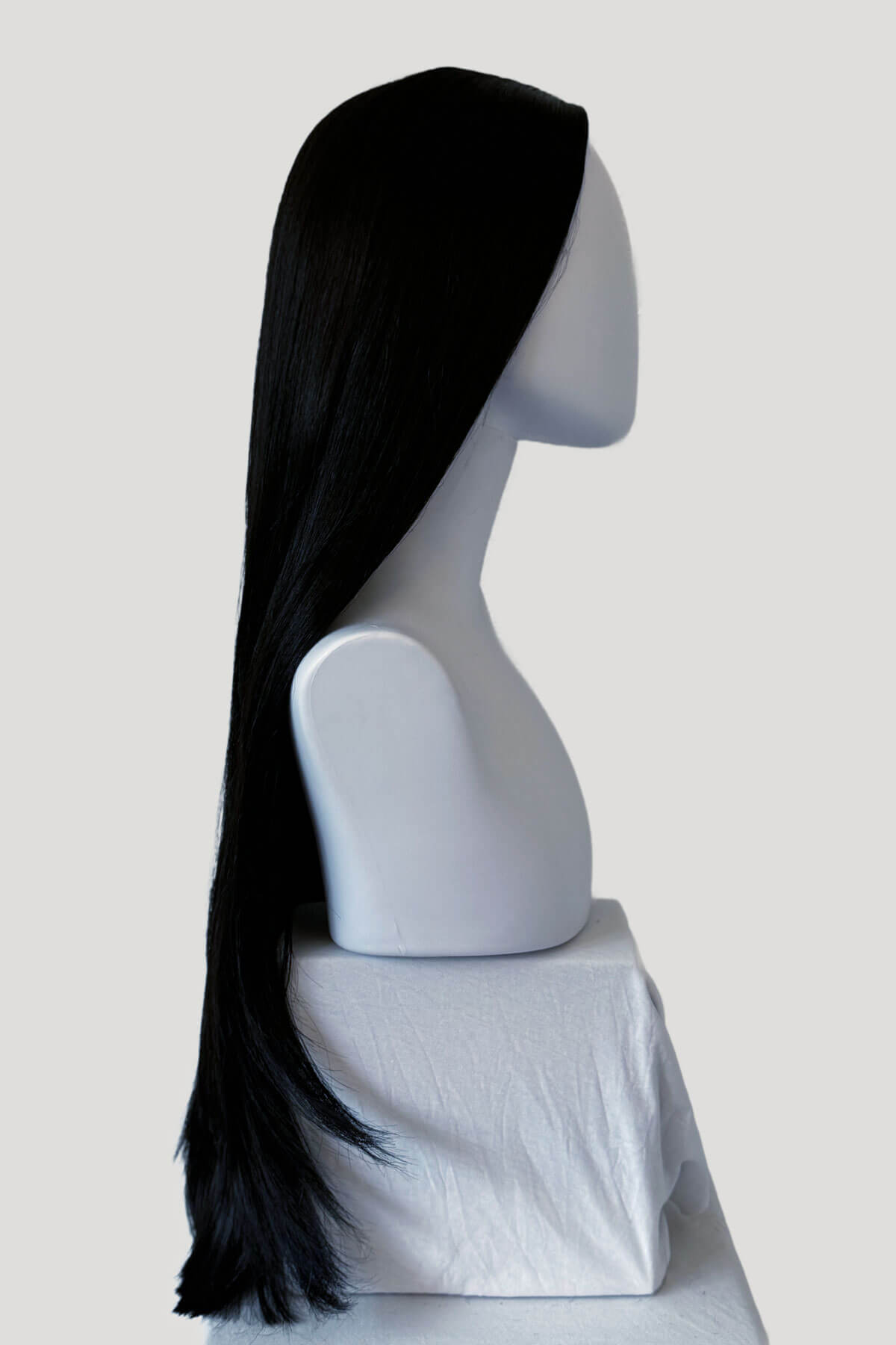 Black wig on a mannequin head against a white background. Long straight black wig with no fringe: Madeline