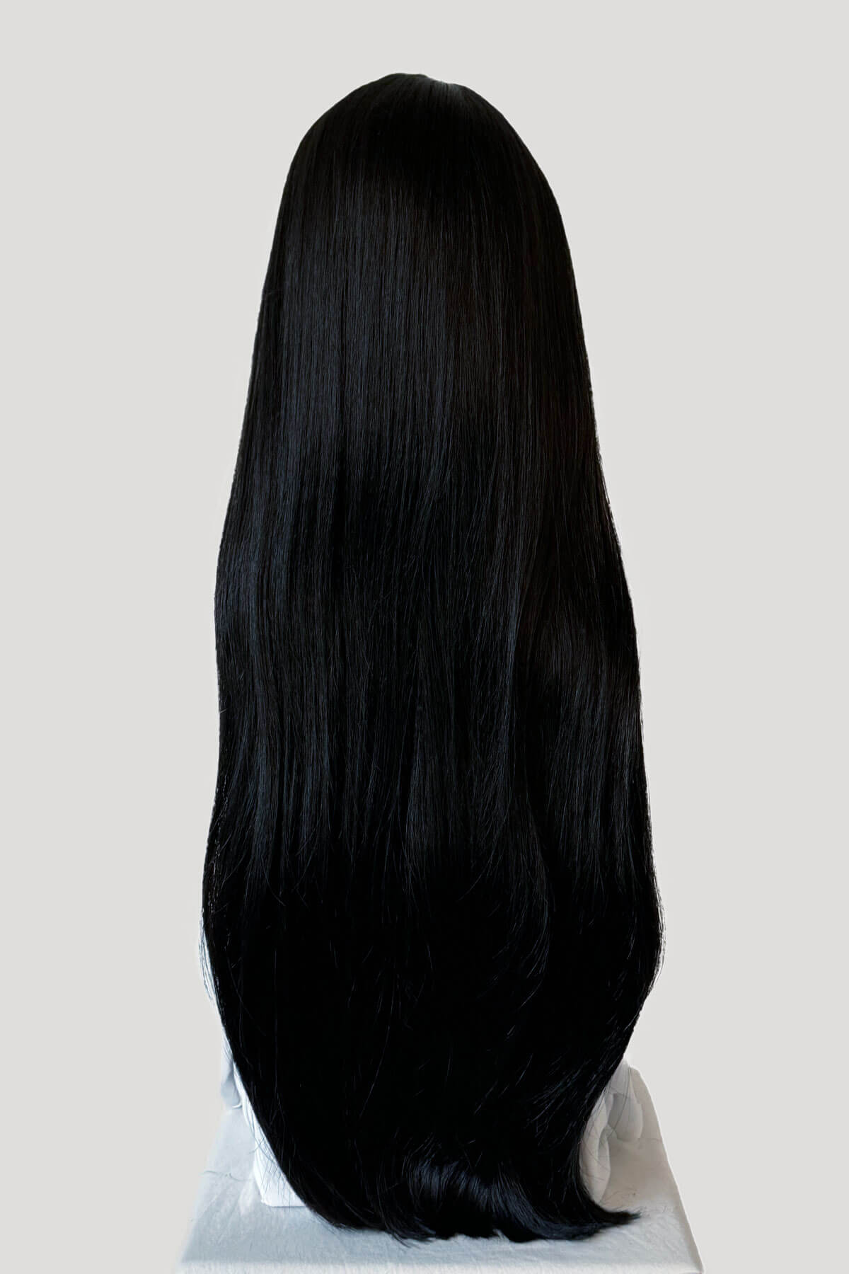 Mannequin head with long black hair on a plain background. Long straight black wig with no fringe: Madeline