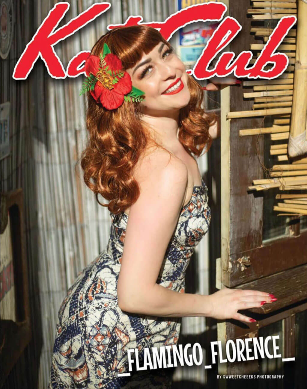 Woman with a floral headpiece playing a piano, with 'Katt Club' and 'Flamingo Florence' text. Auburn pinup style wig, finger waved with short fringe, 1950s style: Heidi