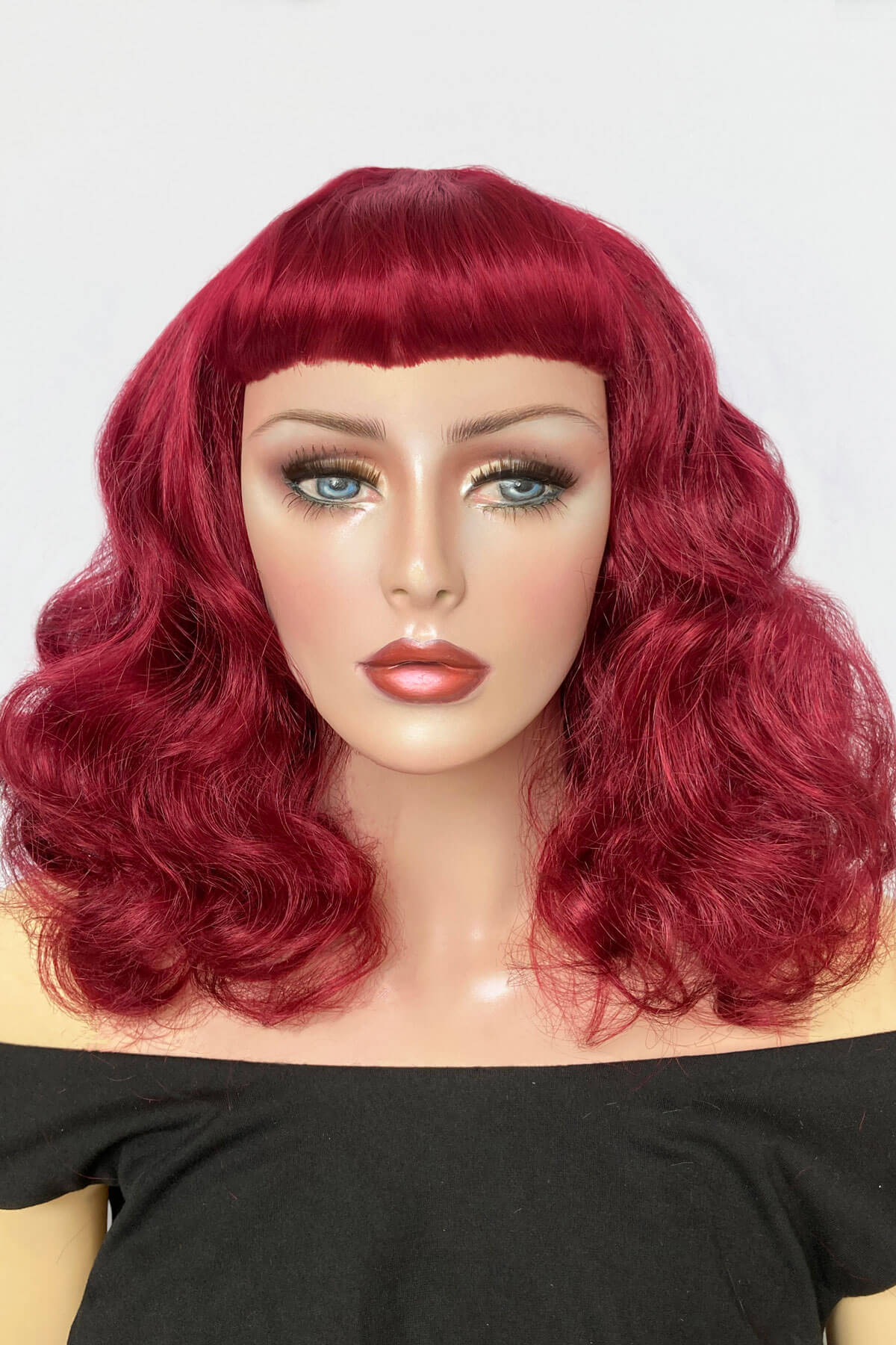 Mannequin head with red wig on a white background. Dark cherry red 1950s pinup style wig: Sandra