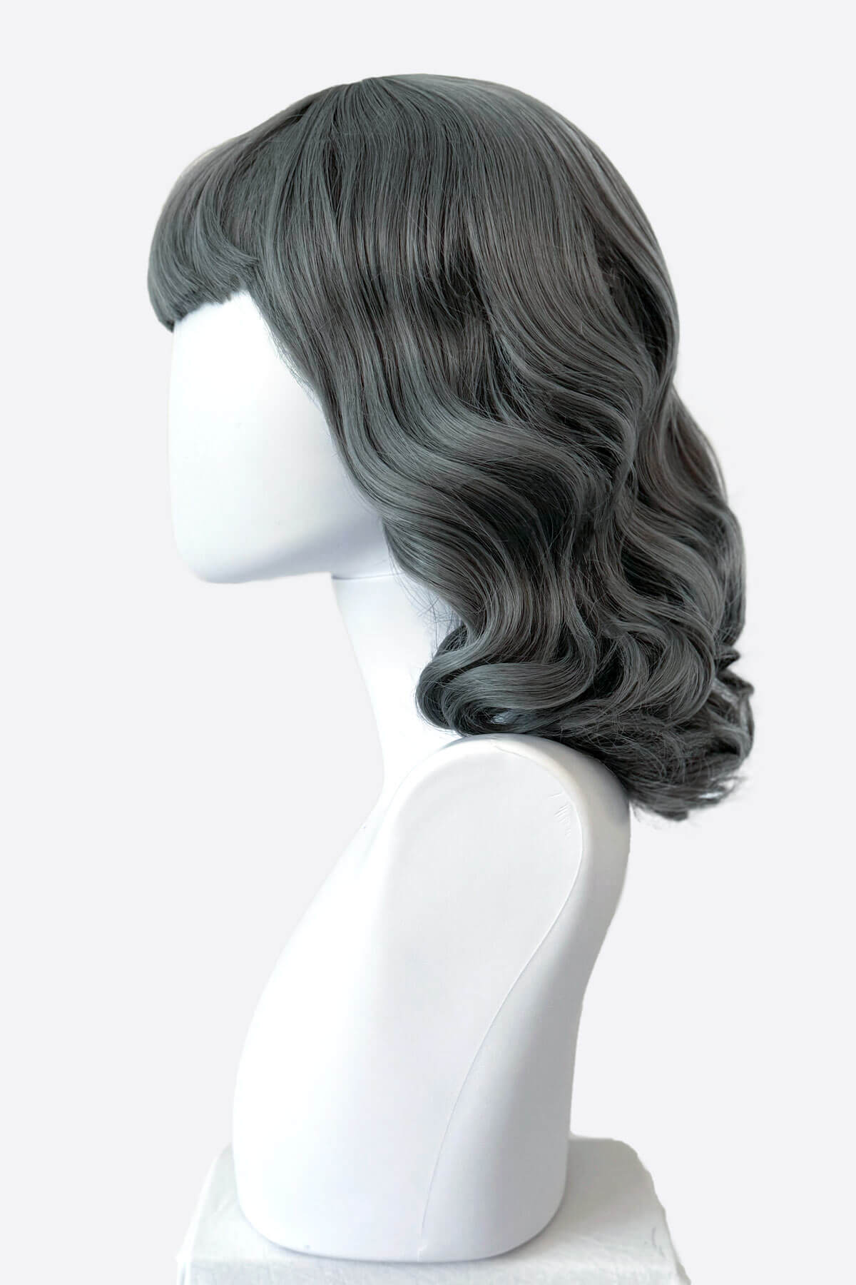 Gray wig on a mannequin head against a white background. Silver-grey pinup style wig with long waves and short fringe, 1950s style: Dotty