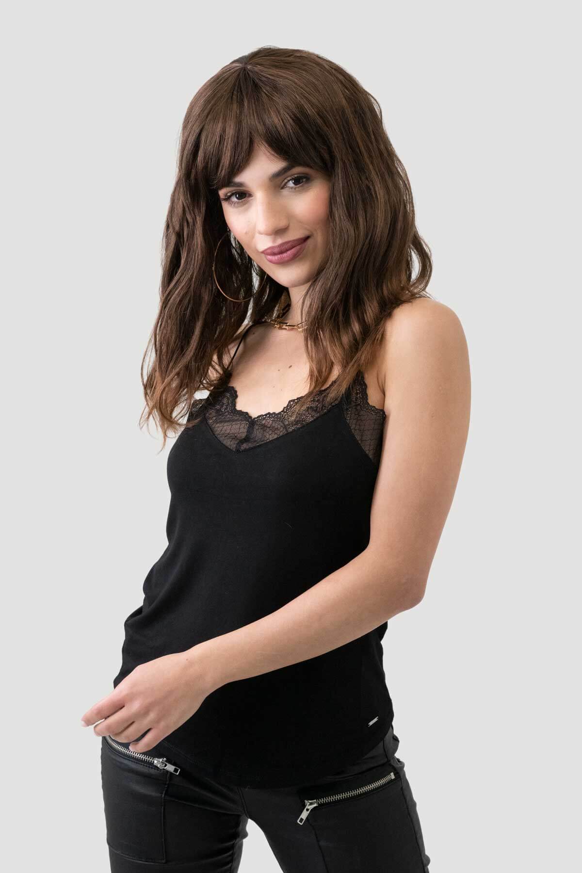 Woman wearing a black sleeveless top with lace detail on a light gray background. Brown long wavy bob (lob) wig with highlights: Melanie