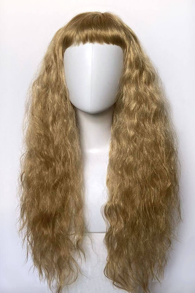 Blonde wig on a mannequin head against a white background. Long wig with crimped mermaid waves: Astrid