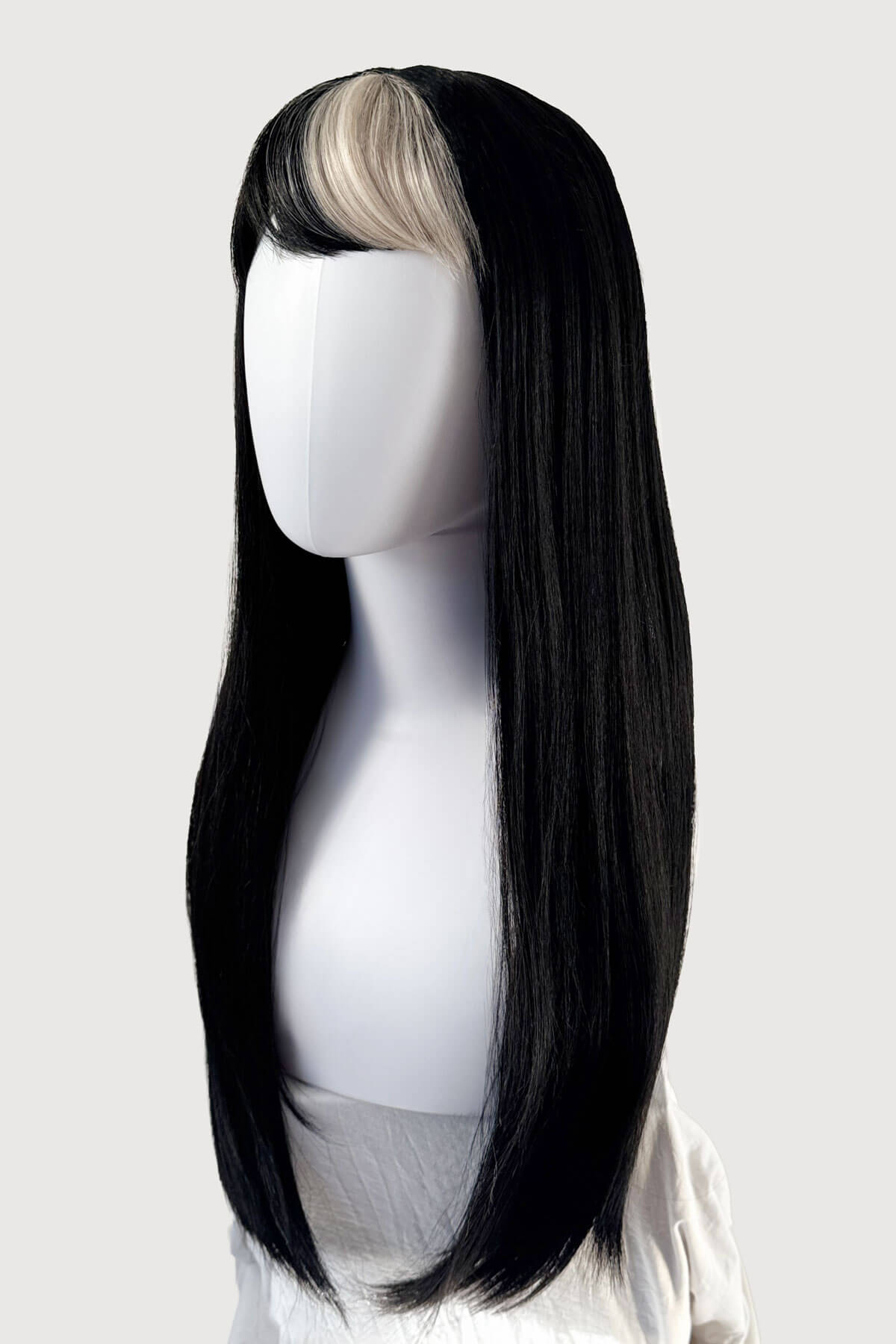Black wig with a blonde section on a mannequin head against a white background. Long, black, straight wig with platinum fringe streak and retro, straight fringe: Imogen