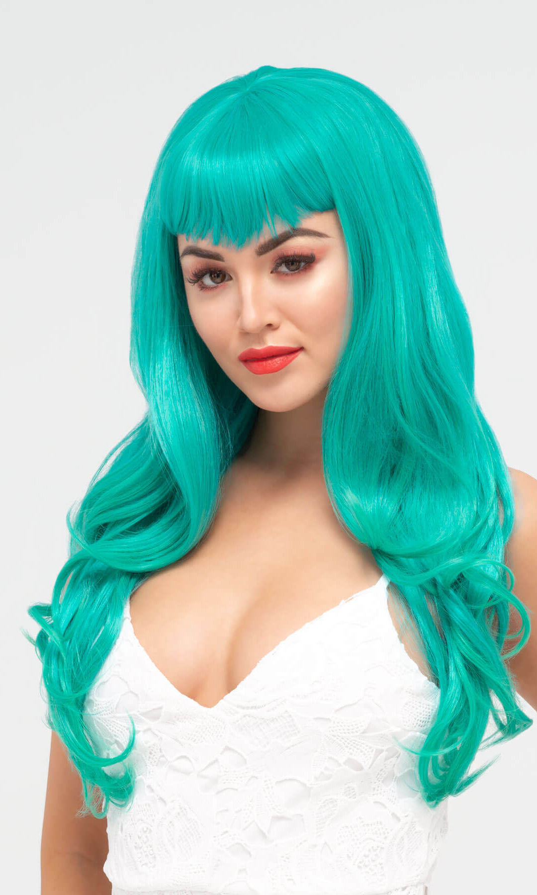 Woman wearing a turquoise wig with bangs on a white background.Long aqua green wig with gentle waves and vintage-style straight fringe: Natalie