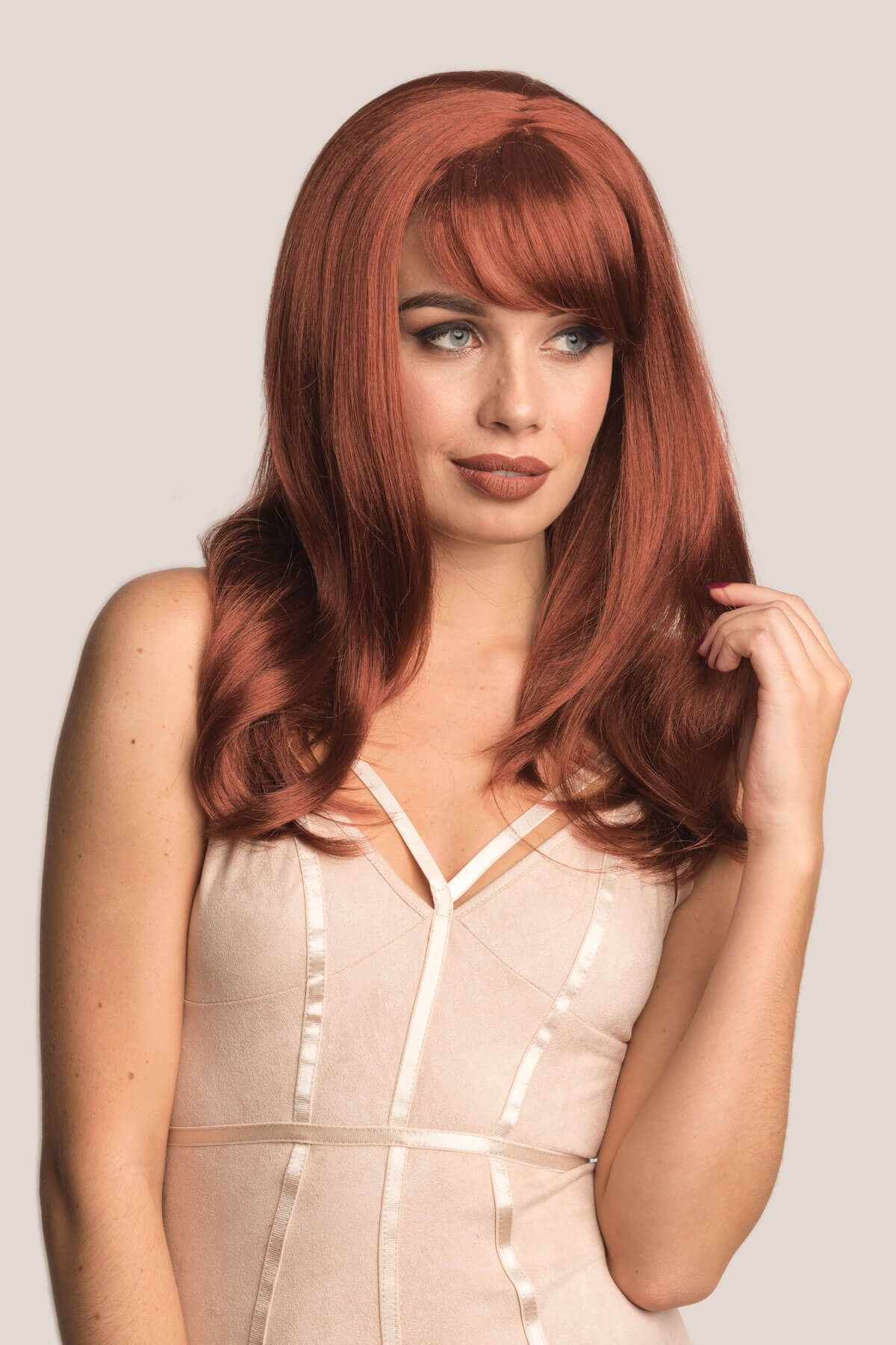 Woman with long red hair posing against a plain background. Long copper red wig, razor cut, face frame style: Eleanor
