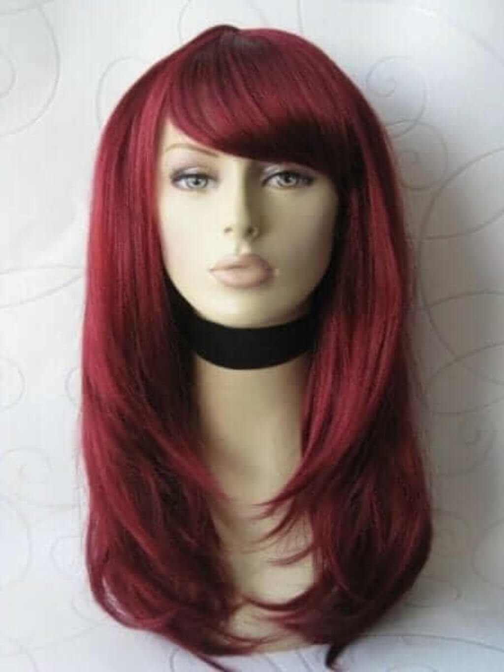 Red wig on a mannequin head against a white background. Long red wig in razor cut, face frame style: Megan