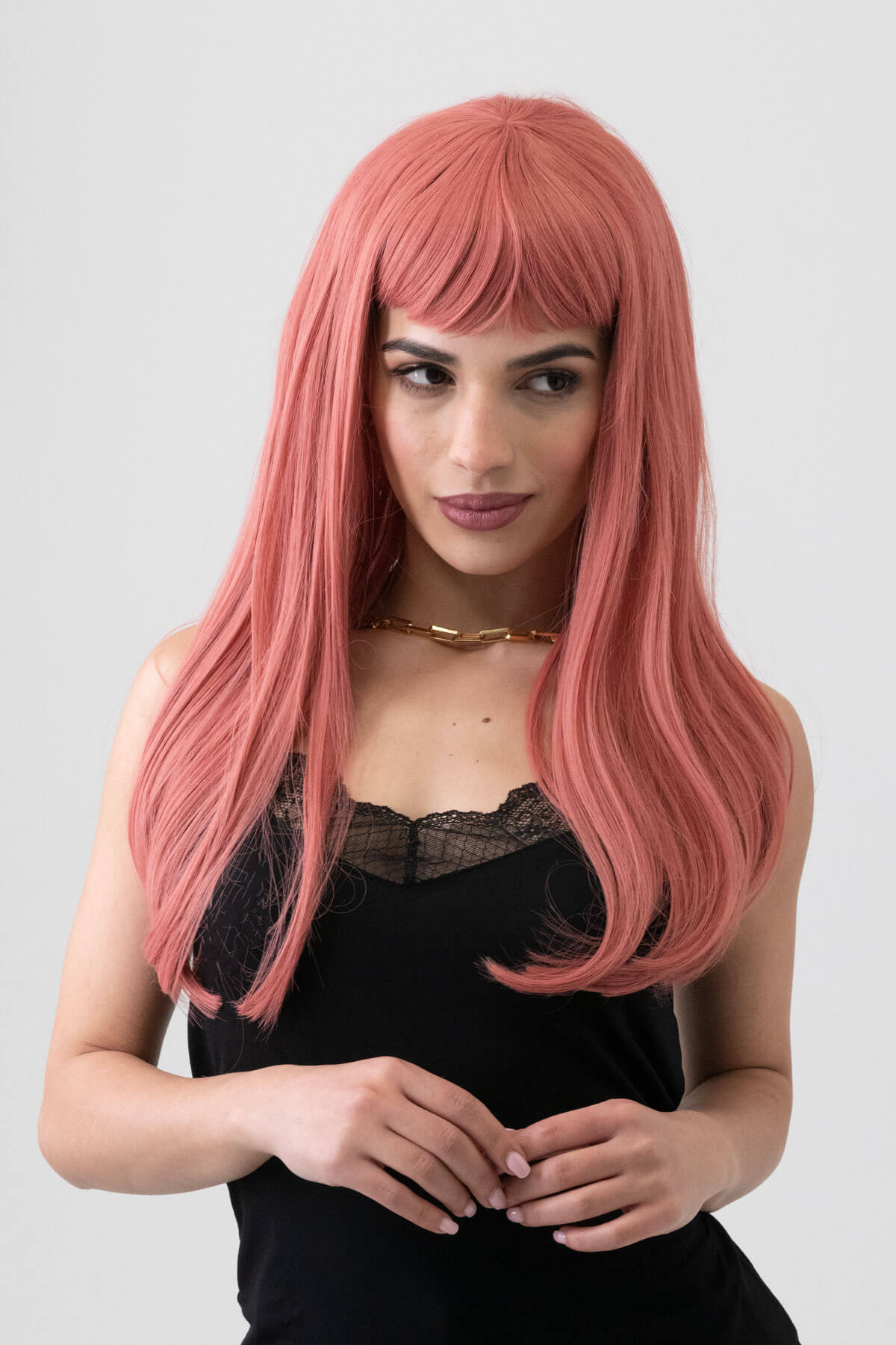Woman with long pink wig wearing a black top on a plain background. Long Pink Wig With Short, Straight Fringe: Stephanie