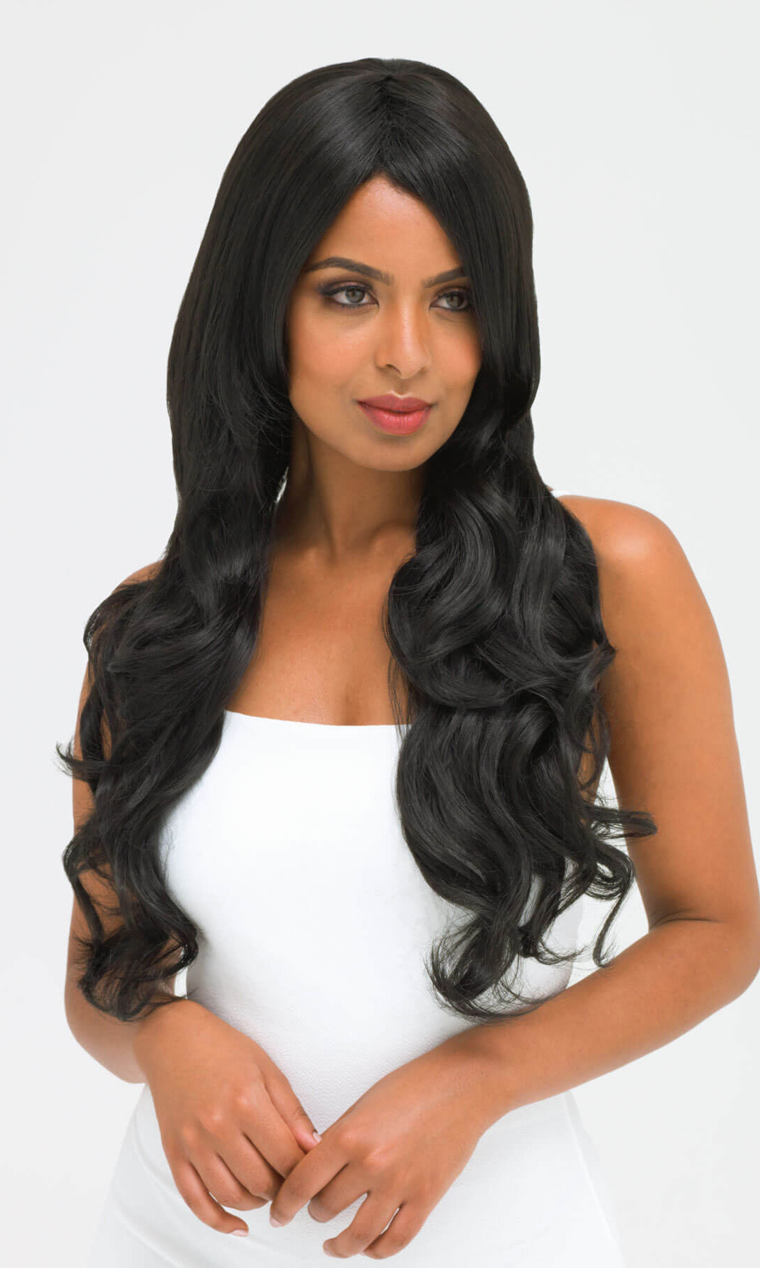 Woman with long black wavy hair wearing a white top on a light gray background. Long wavy black wig with side-sweeping Fringe: Charlotte