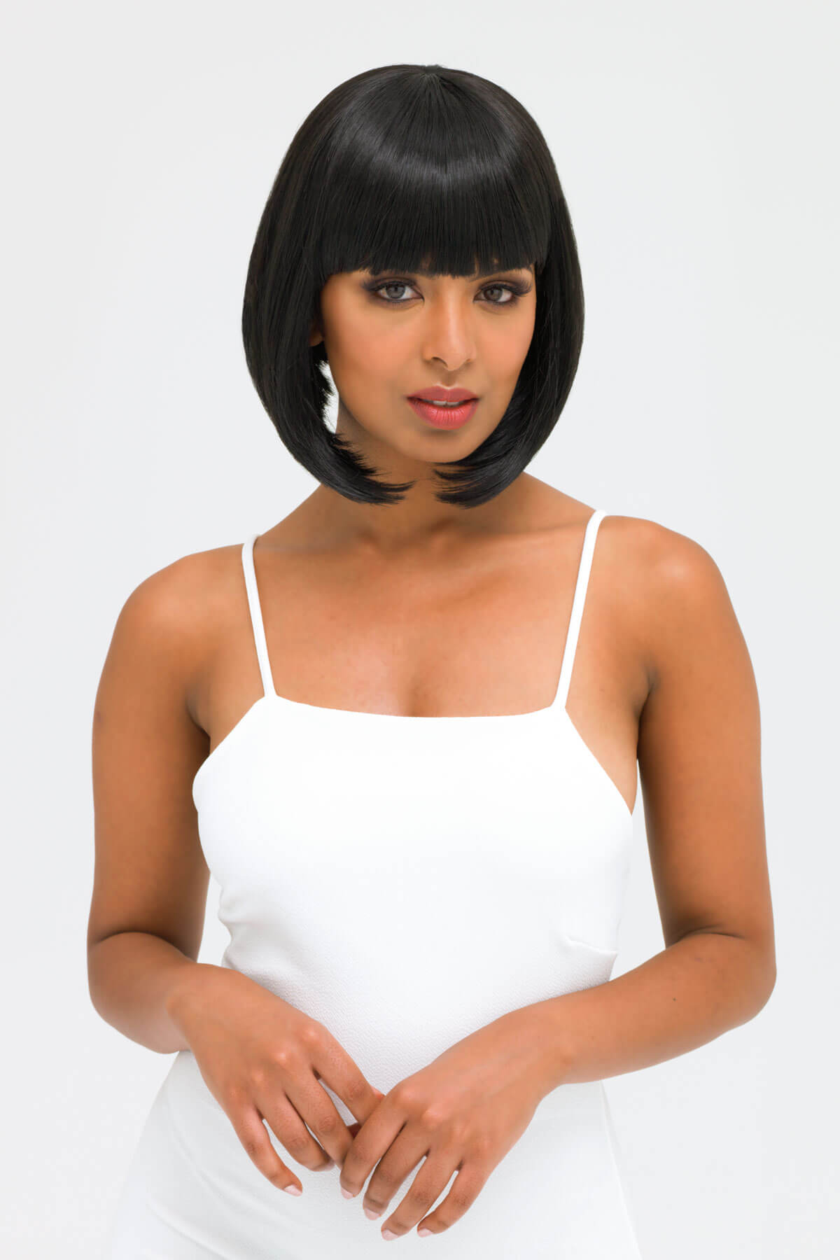 Woman wearing a white dress with a plain background. Black inverted bob wig: Chloe