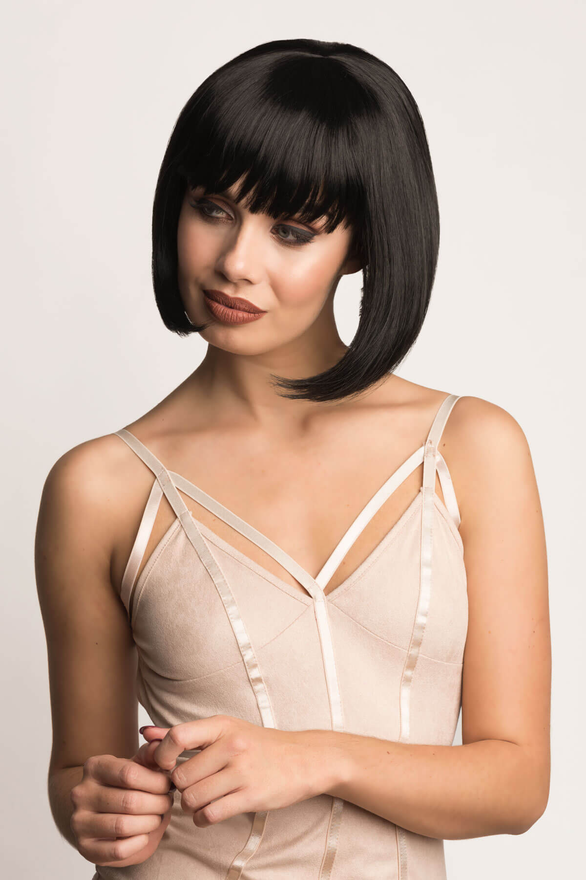 Woman wearing a beige satin slip against a plain background. Black inverted bob wig: Chloe