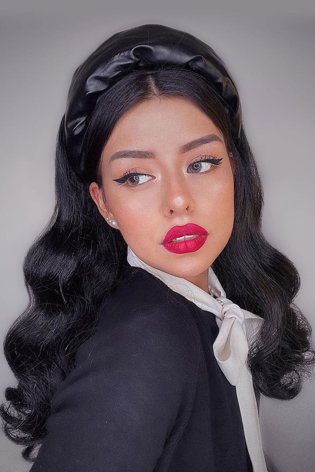 Woman with styled hair and makeup wearing a black headscarf and outfit. Black 1950s pinup style wig, curled with short fringe: Milena