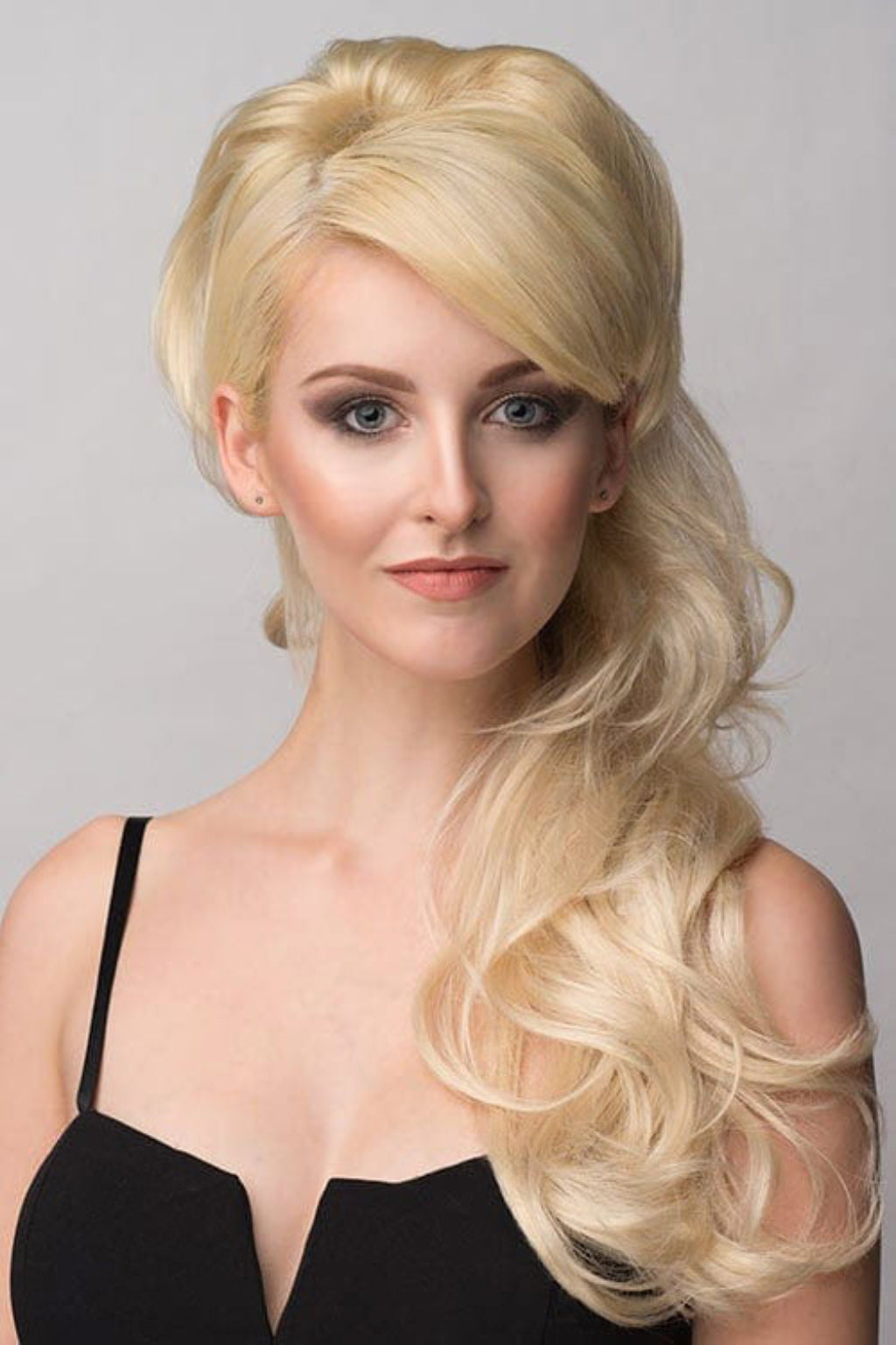A woman wearing a black dress and a double volume hairpiece extension with gentle waves.