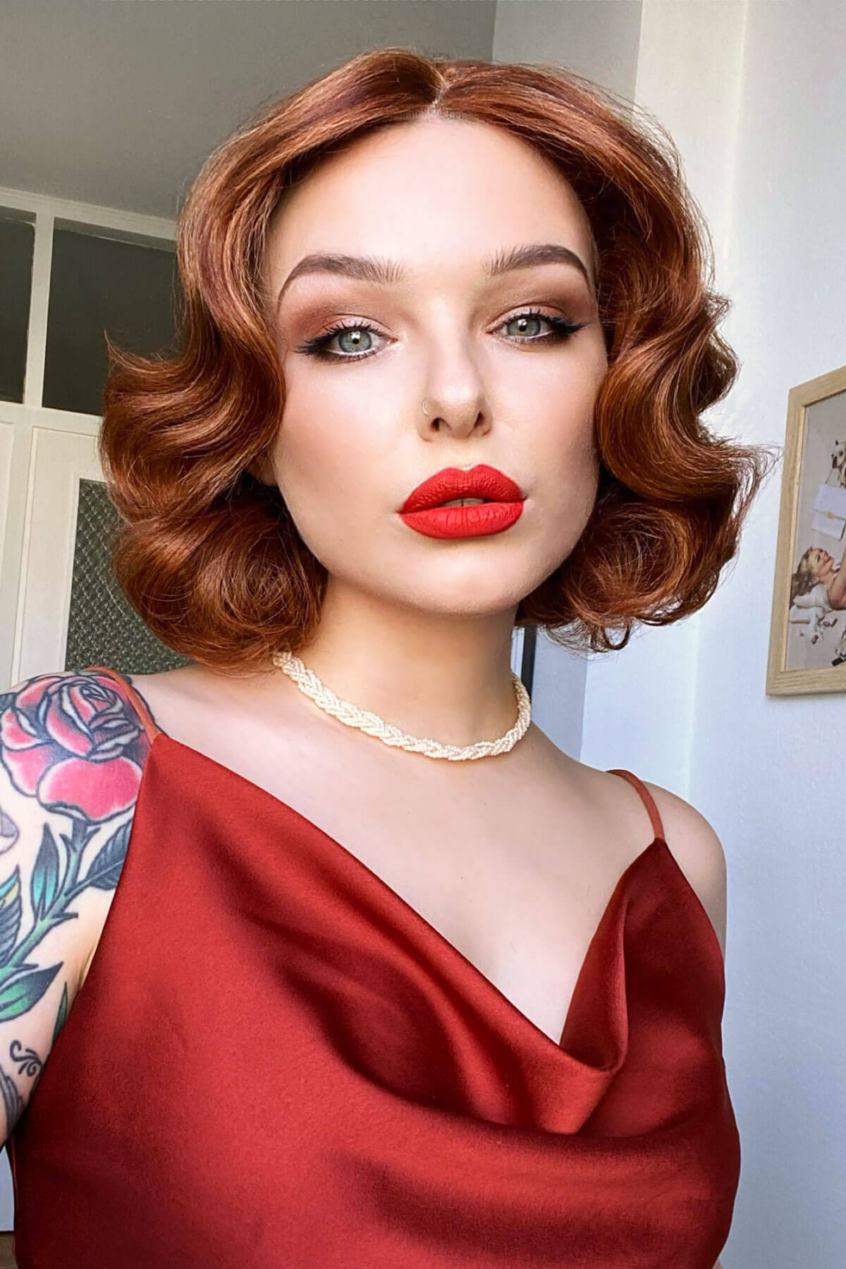 Woman in a red dress with tattoos on her arm, wearing a necklace. Red, auburn & blonde pinup wig, lace front, vintage style: Ginny