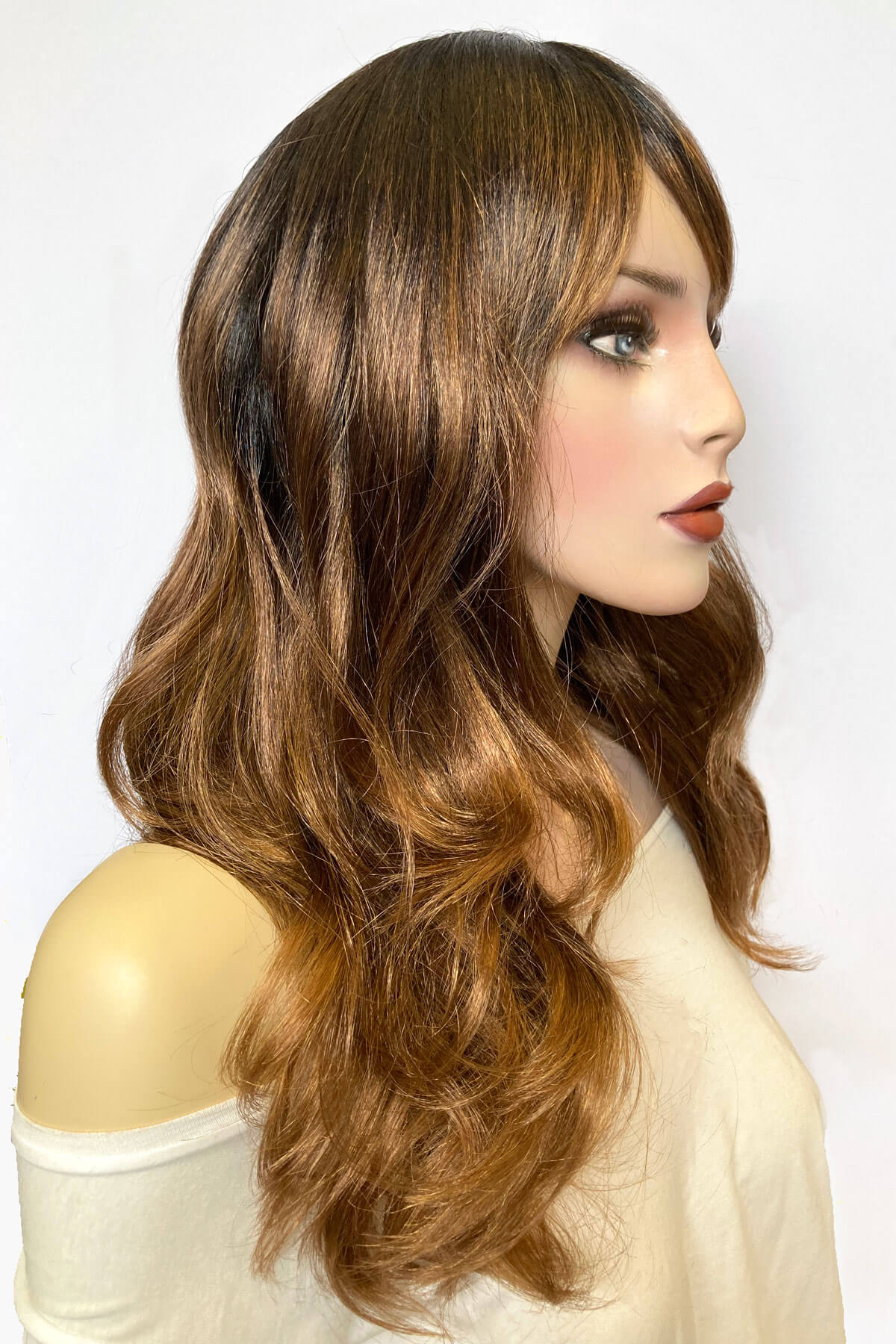 Woman with long, wavy brown hair styled in a side part against a white background. Ombre brown wig with reddish brown highlights & waves: Serenity