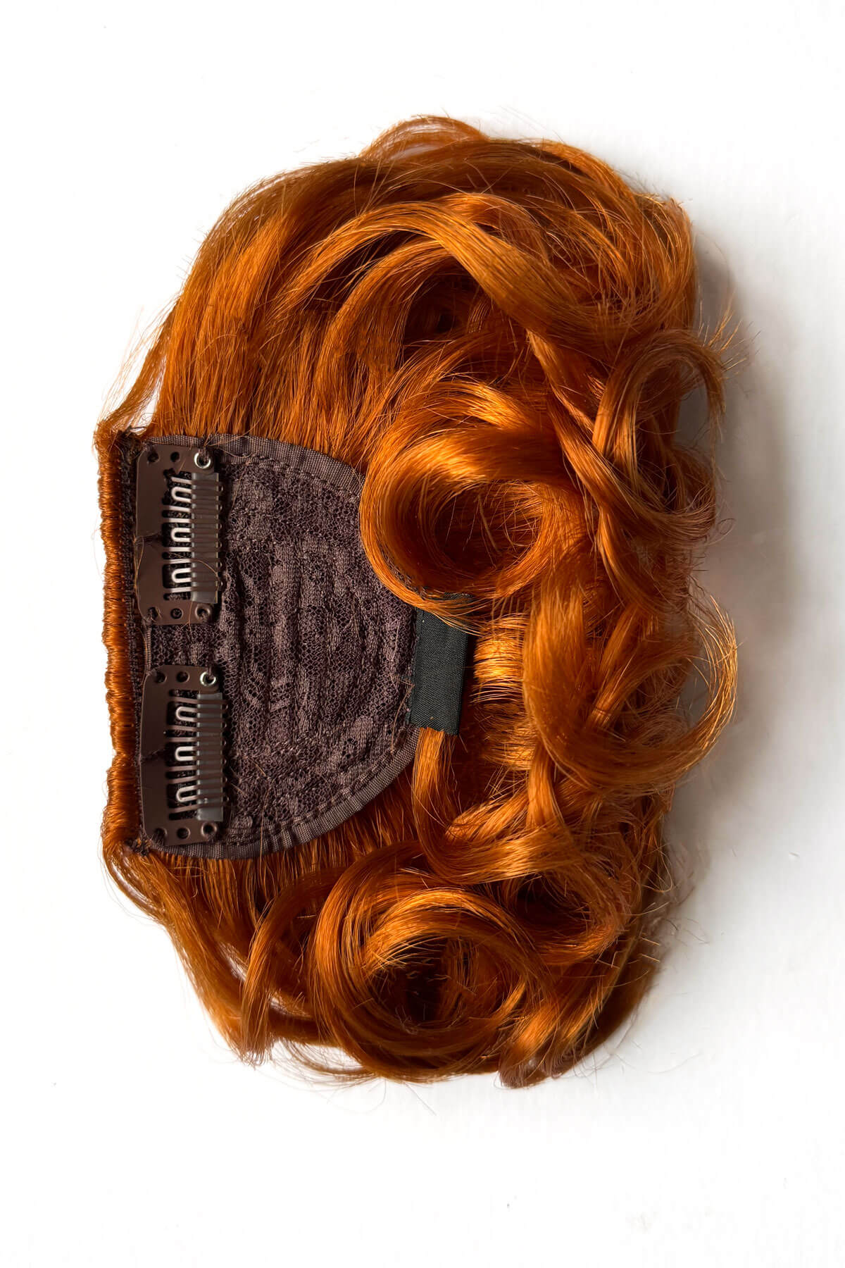Reddish-brown hairpiece with a clip on a white background. Curly 1940s style clip-in fringe hairpiece/clip-in bangs: Bunny ginger