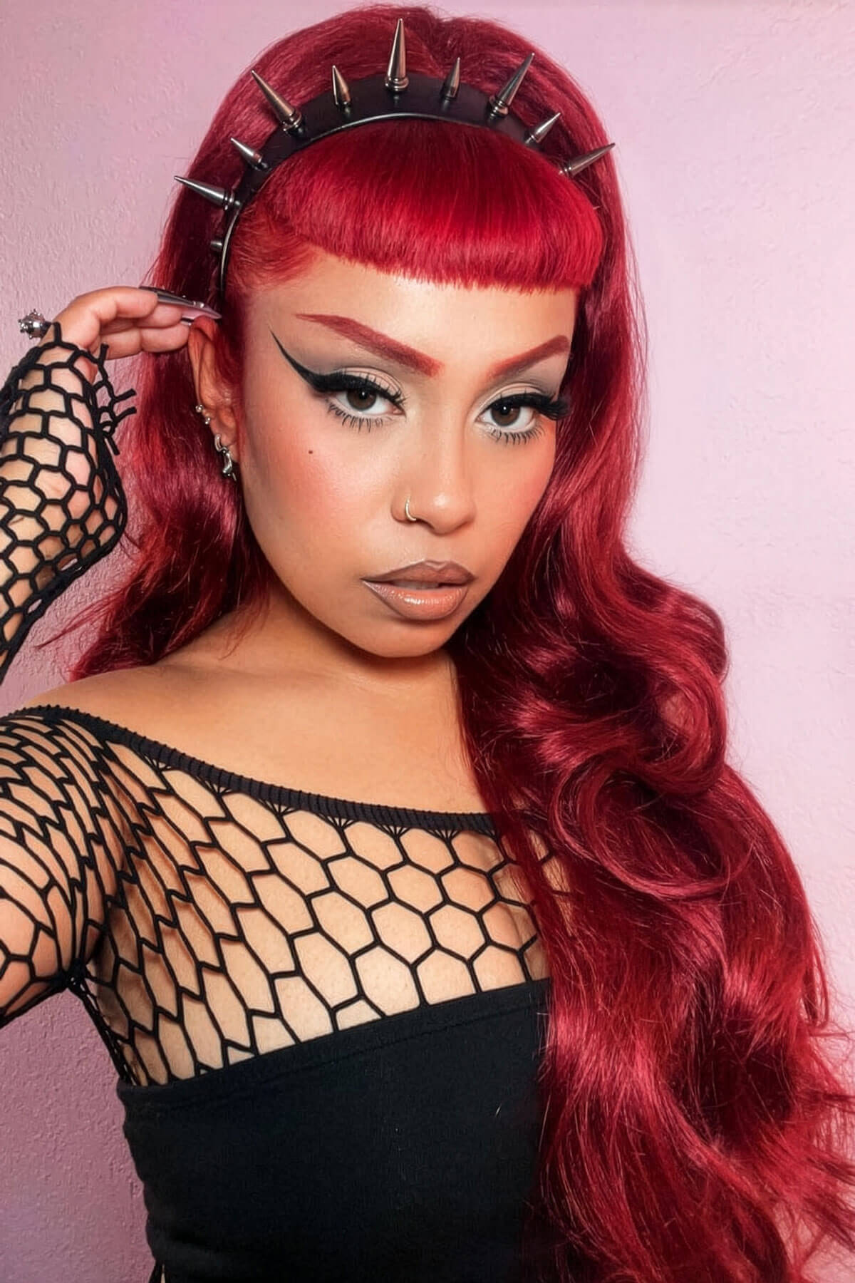 Woman with vibrant red hair and a spiked headband against a pink background. High crown long, wavy half wig and volume ring, copper and cherry red: Bardot 350-39