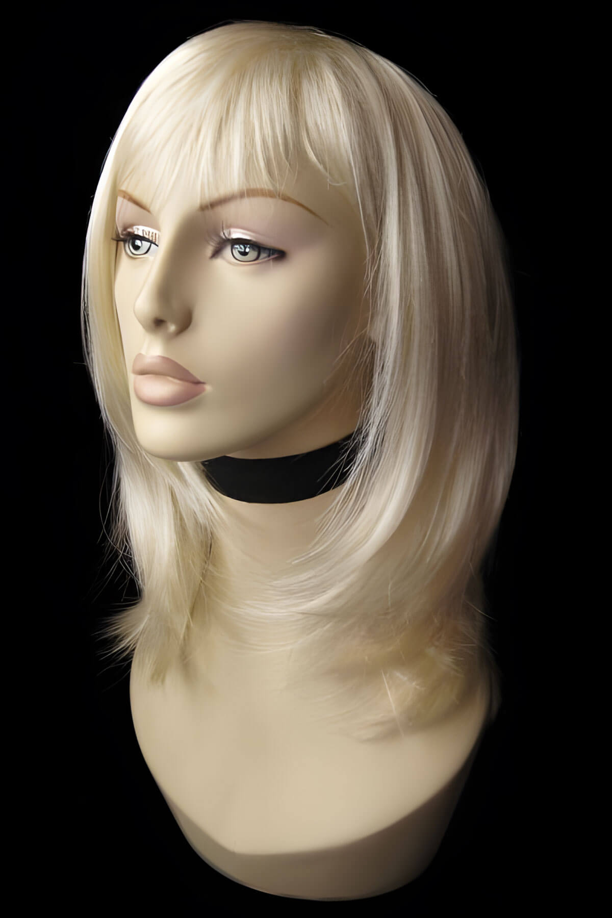 Blonde wig on a mannequin head against a black background. Blonde mid-length wig, face frame, layered style: Lilly champagne blonde 613