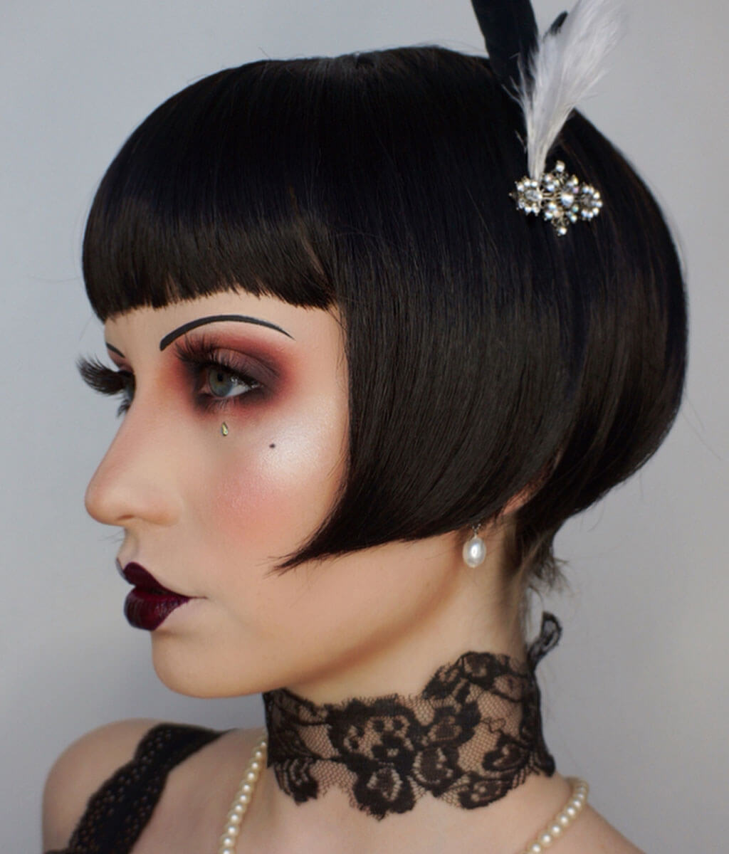 Woman with vintage-style makeup and hair, wearing a black lace choker and pearl necklace. Louise Brooks style wig, short black bob: Brooks