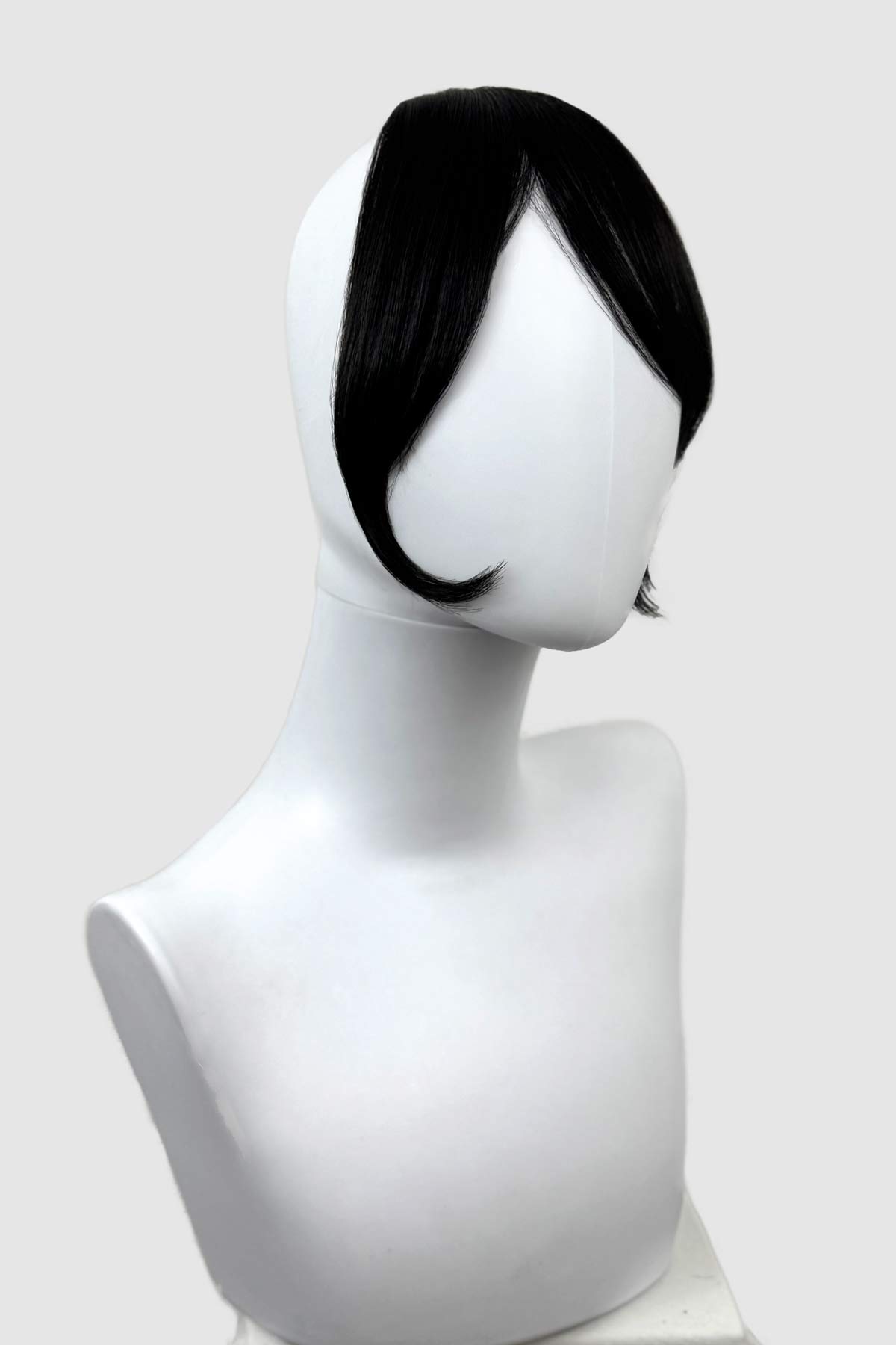 Black wig on a white mannequin head against a white background. Clip in fringe hairpiece/clip-in curtain bangs, with long, face framing wisps: Sabrina black 1b