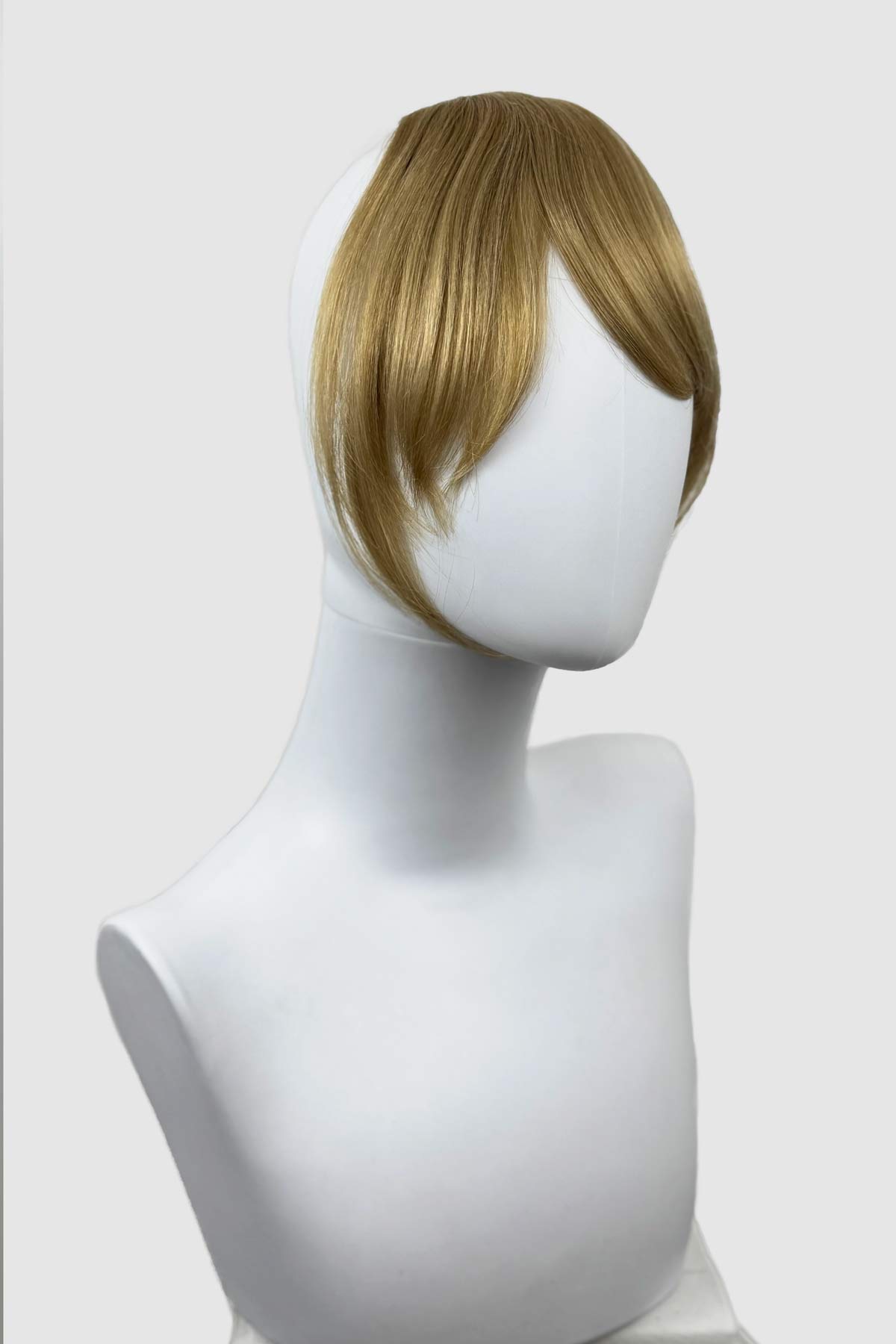 Mannequin head with a blonde wig on a white background. Clip in fringe hairpiece/clip-in curtain bangs, with long, face framing wisps: Sabrina blonde 24H613