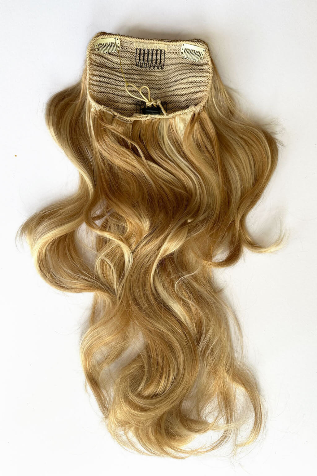 Blonde hair extension with a clip on a white background. Double volume hairpiece extension: Naomi warm blonde 24BH613