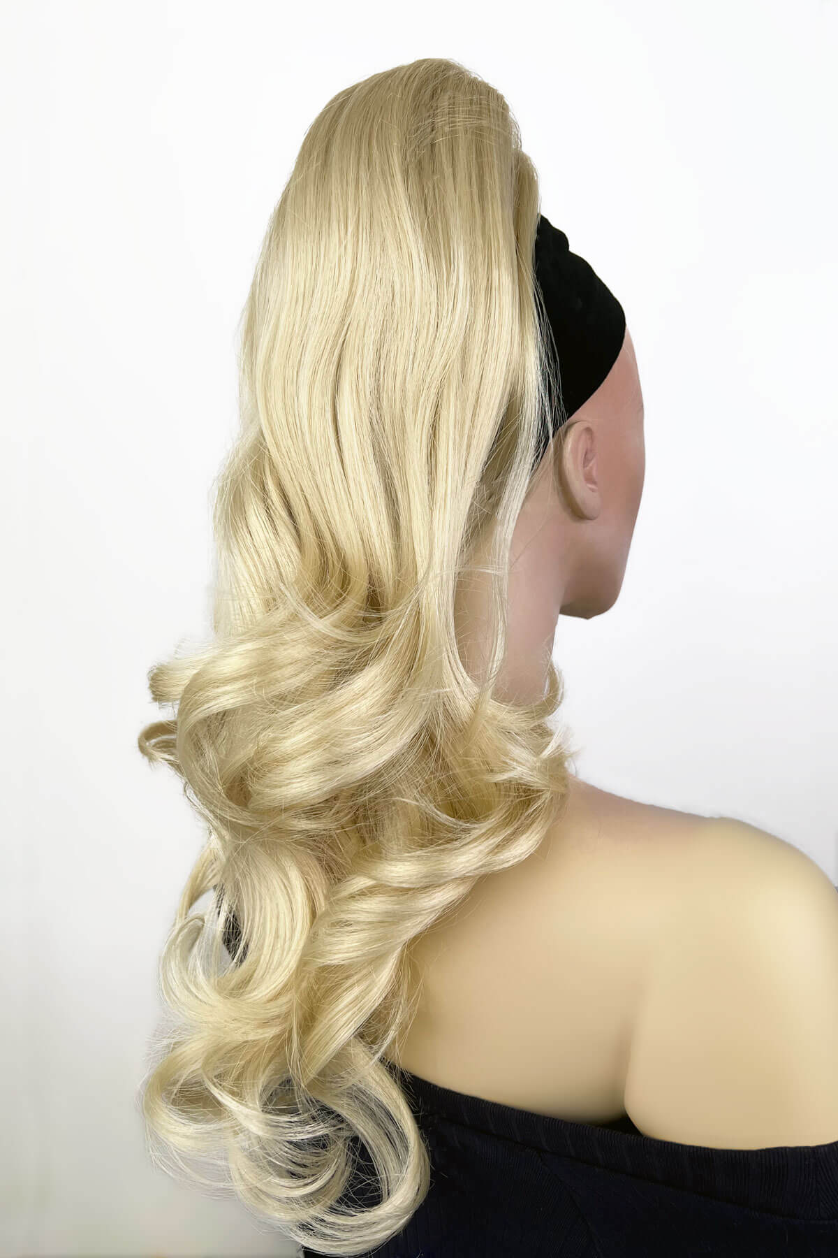 Blonde wig on a mannequin head against a white background. Wavy, long ponytail hairpiece extension: Casey champagne blonde 613