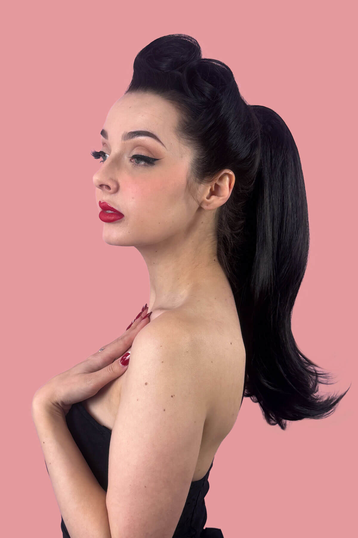 Woman with a long, black, high ponytail against a pink background. Long ponytail hairpiece, straight with flick: Clarisa black 1B