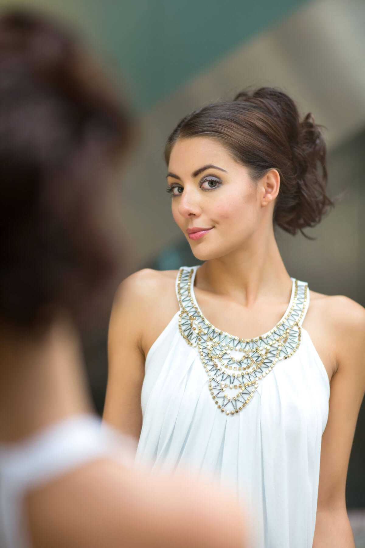 Woman wearing a white dress with a decorative necklace. Clip in hairpiece, ponytail, short, flexihair: Leela chestnut brown 8