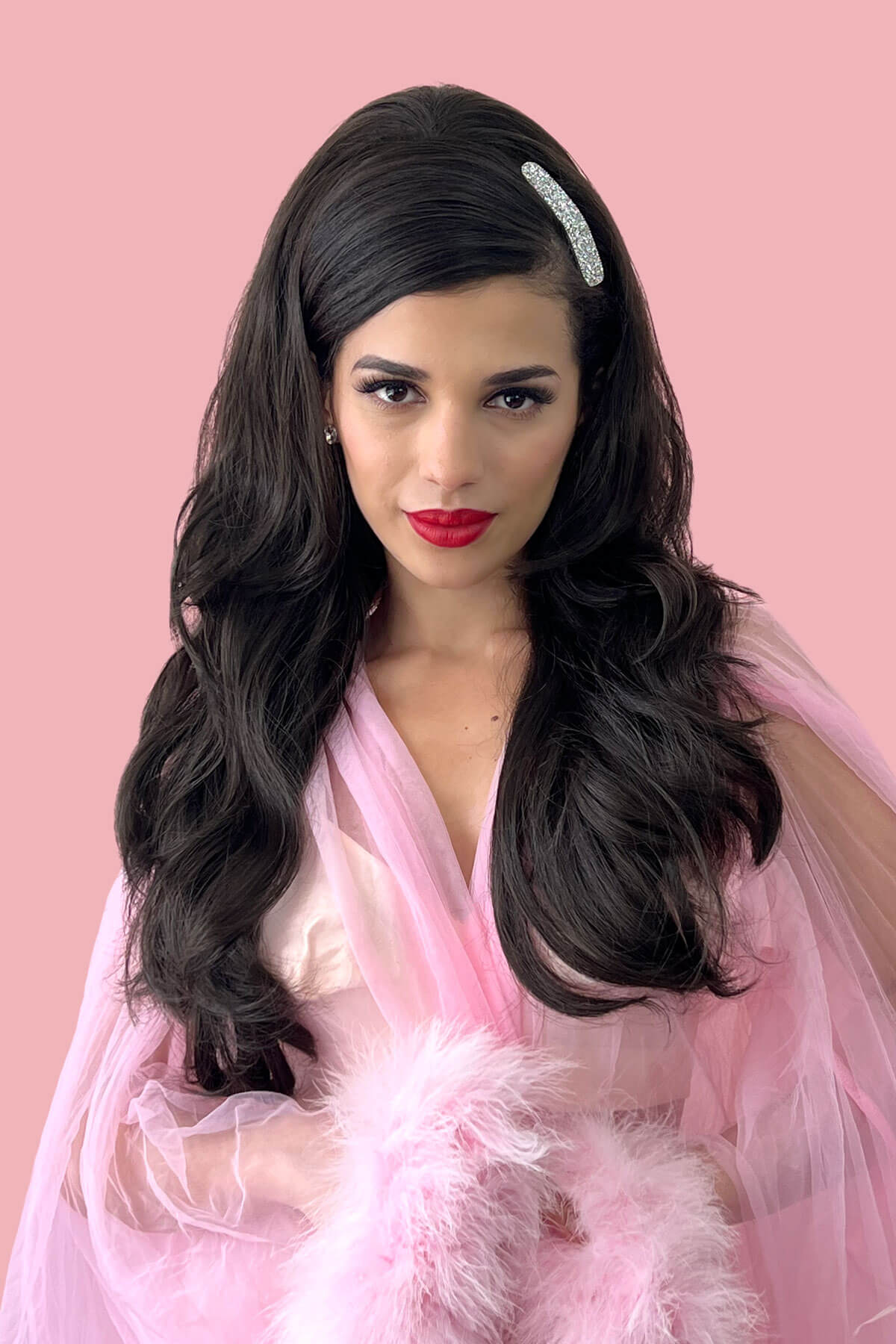 Woman with long dark hair and red lipstick wearing a pink dress against a pink background. High crown long layered half wig and volume ring Helena brown 4