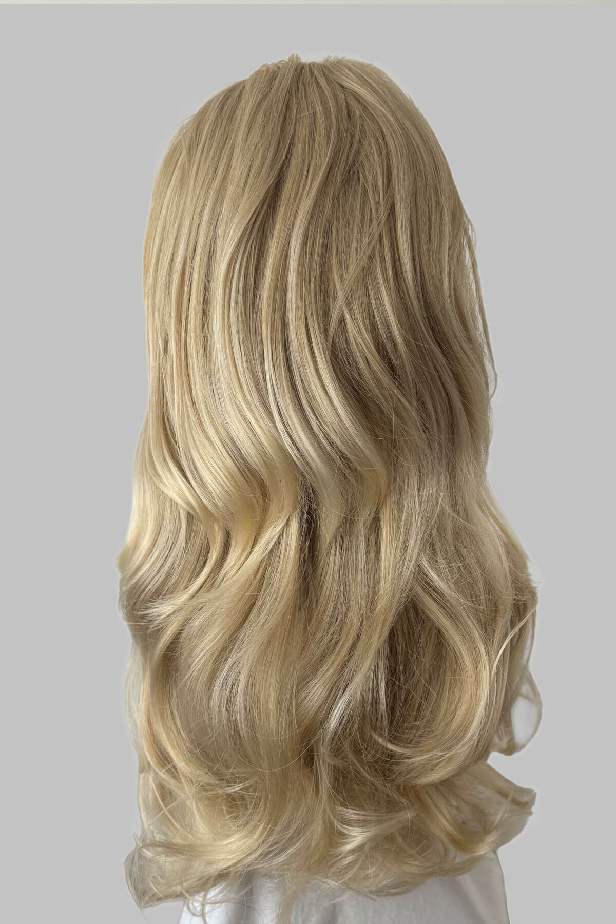 Blonde wig with wavy hair on a grey background. Long blonde 3/4 hairpiece (half wig), big loose curls: Zara blonde 613T24