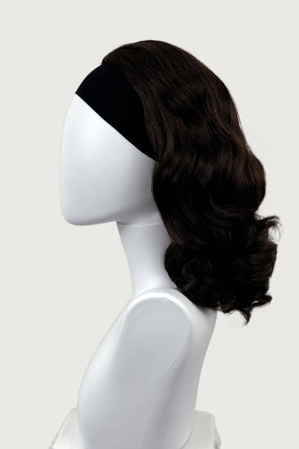 Dark chocolate brownwig on a mannequin head against a white background viewed  from the side. 1950s style shoulder length half wig hairpiece with beautiful vintage waves: Onyx dark chocolate brown 6