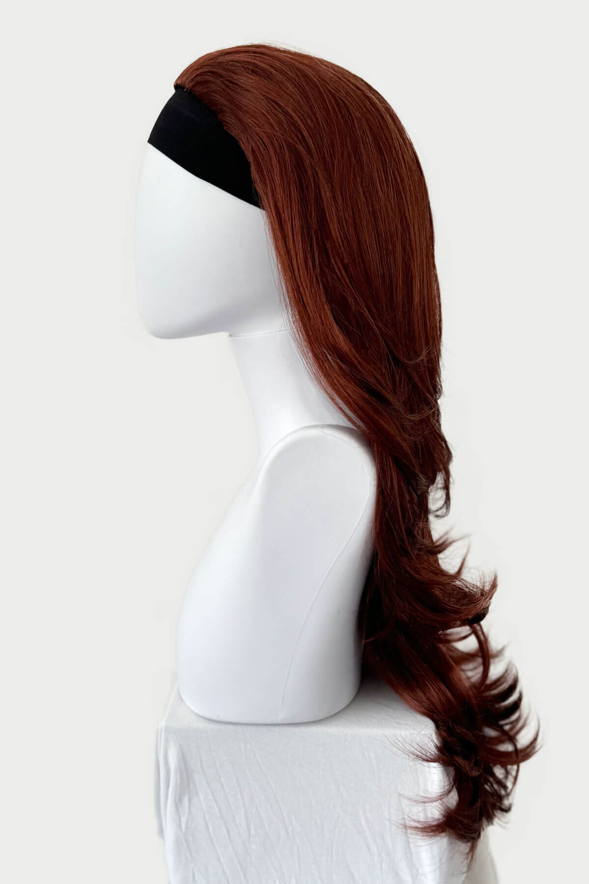 Brown wig on a mannequin head against a white background. Red half wig hairpiece (3/4 wig), gentle curls: Ivy copper 130