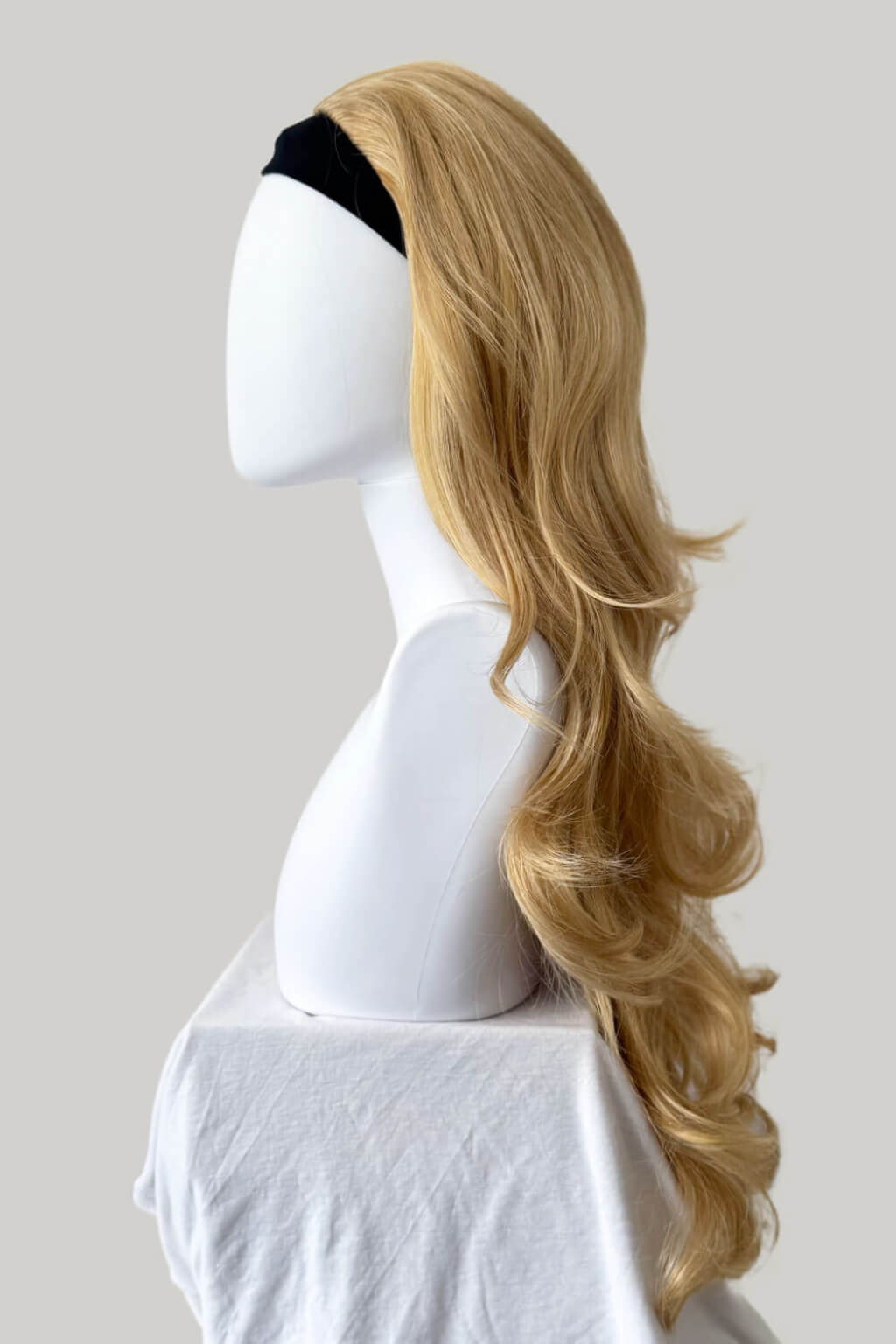Blonde wig on a mannequin head against a plain background. Suki - Super Full Volume, Extra Long, Bouncy Brown Half Wig blonde 24BH613
