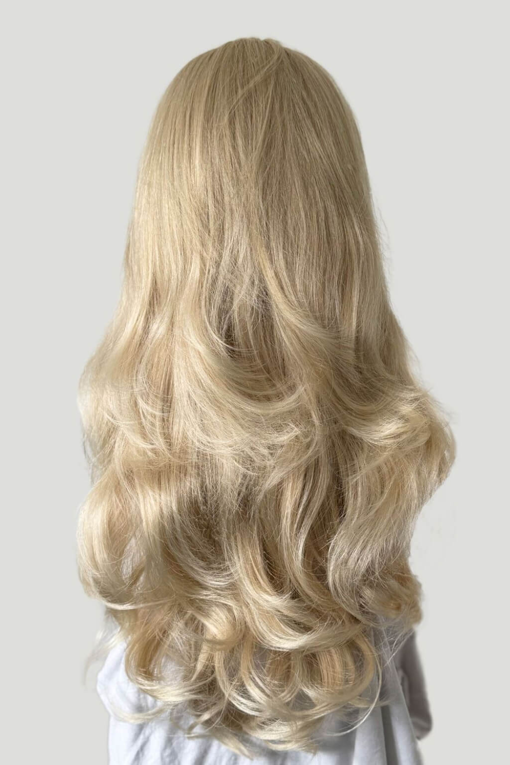 A long, wavy blonde wig displayed on a white mannequin head and shoulders against a light grey background. Blonde half wig hairpiece (3/4 wig), loose curls: Suki blonde 613T24