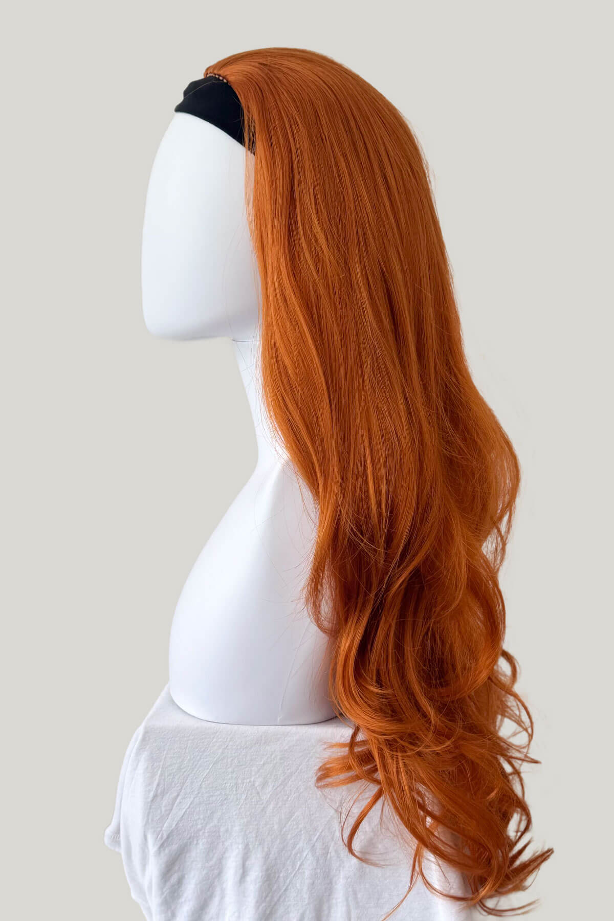 Ginger wig on a mannequin head against a plain background. Ginger half wig (3/4 hairpiece) with long waves: Keegan