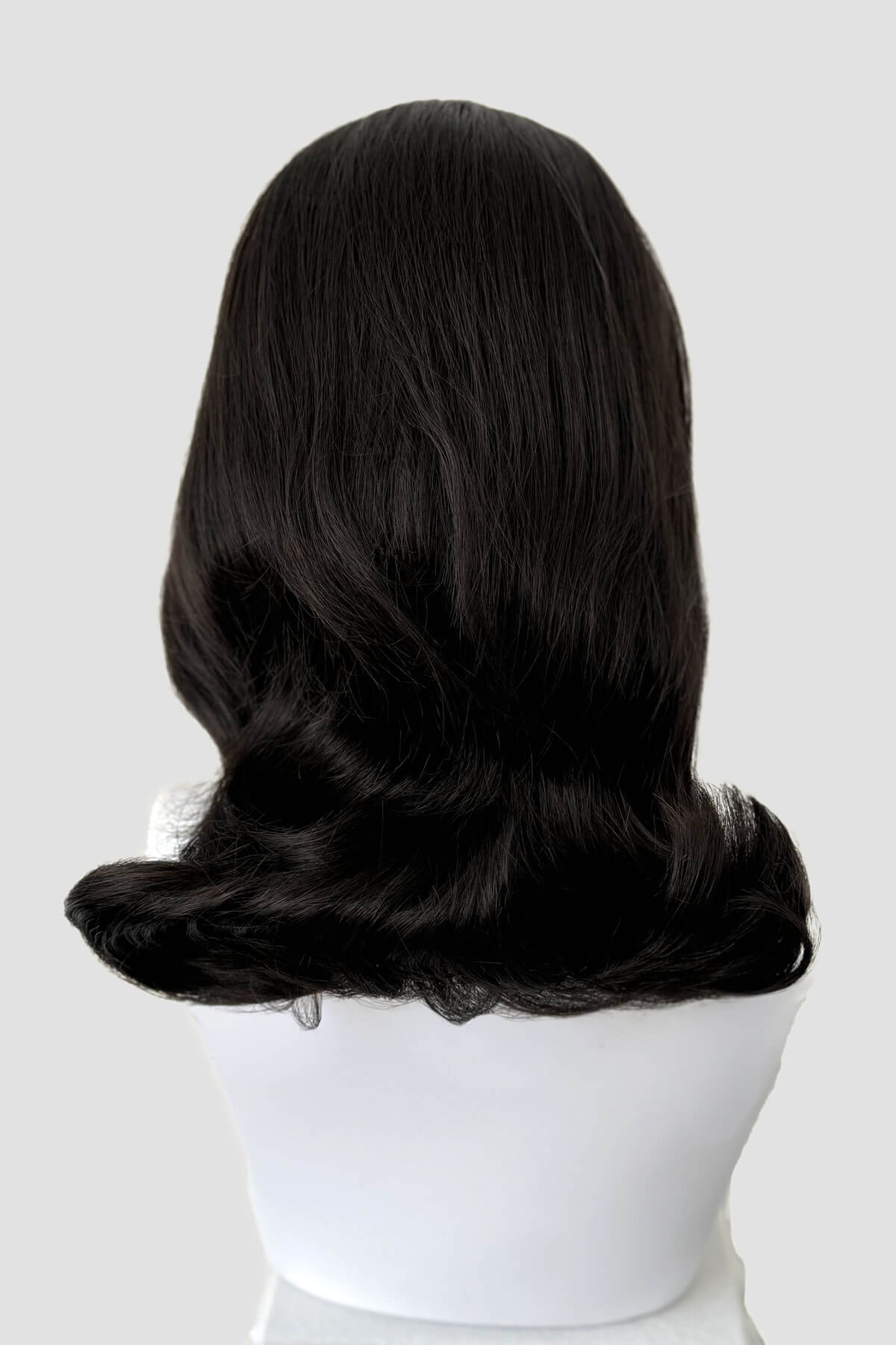 Dark brown wig on a white mannequin head against a light gray background. 1960s half wig hairpiece, flicked, hair flip: Philippa dark brown 4