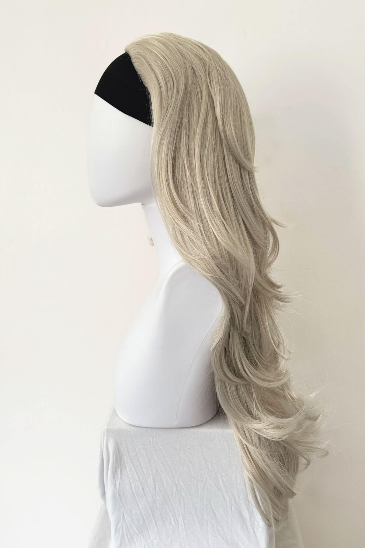 Blonde wig on a mannequin head against a white background. Silver half wig hairpiece (3/4 wig), loose curls: Tahlia