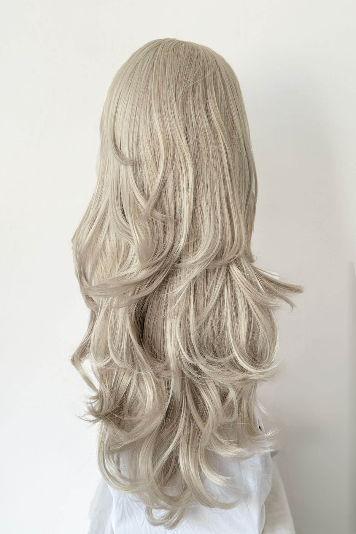 Blonde wig with long, wavy hair on a white background. Silver half wig hairpiece (3/4 wig), loose curls: Tahlia