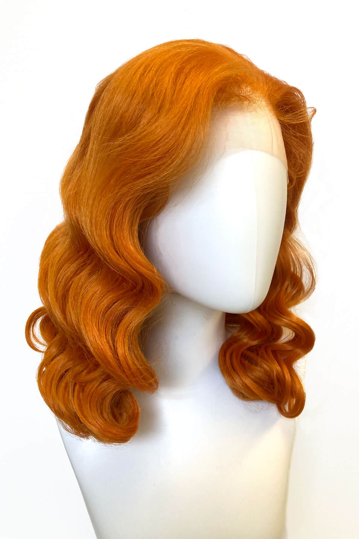 Orange wig on a mannequin head against a white background. Ginger pinup lace front wig, Dita Von Teese style vintage style wig with finger waves Lula