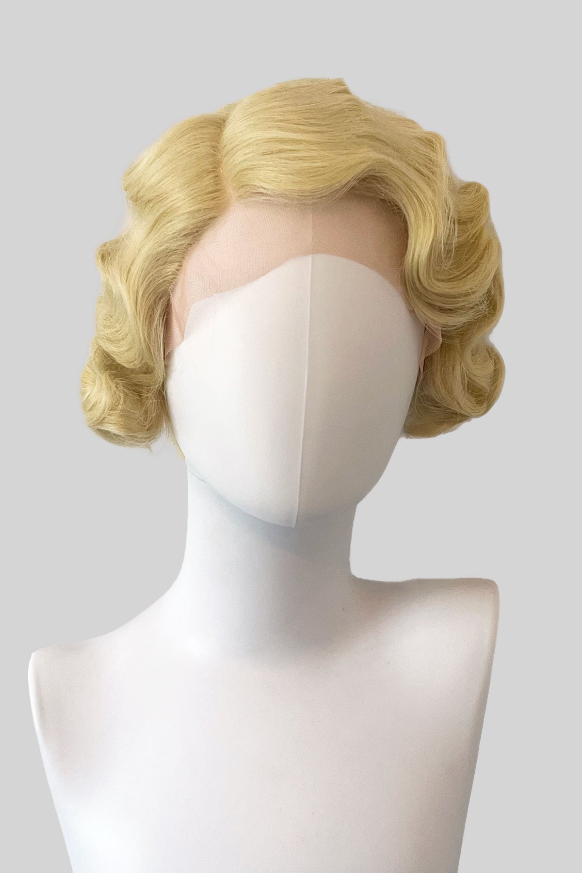 Blonde wig on a mannequin head against a plain background. Blonde pinup wig, lace front, vintage style: Odette blonde 613