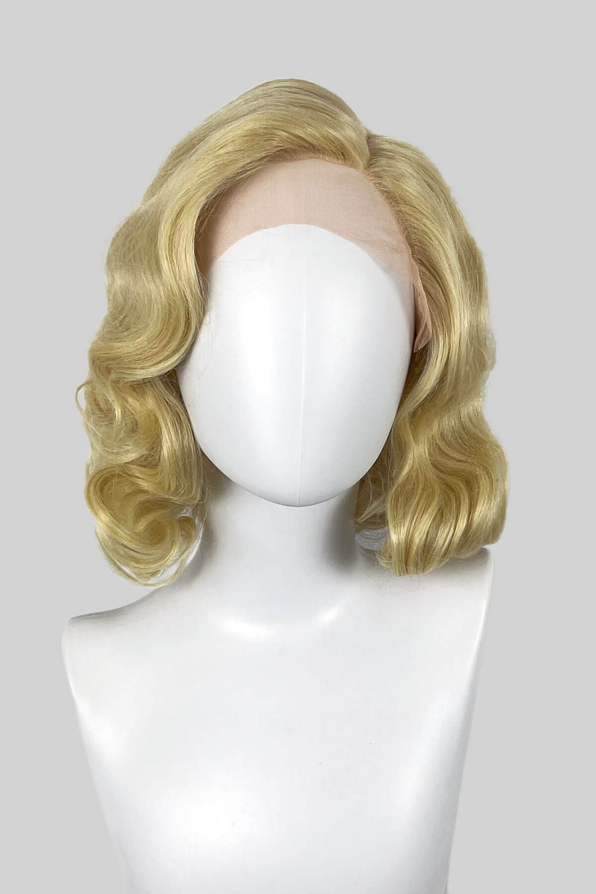 Blonde wig on a mannequin head against a white background. Blonde lacefront wig, pinup/vintage style, mid length with finger waves: Della creamy blonde 613