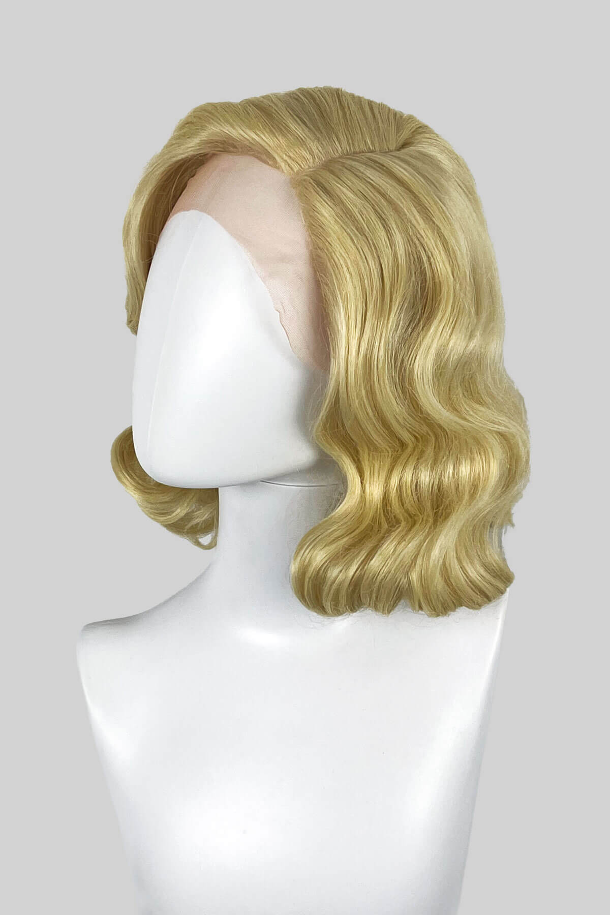 Blonde wig on a mannequin head against a white background. Blonde lacefront wig, pinup/vintage style, mid length with finger waves: Della creamy blonde 613
